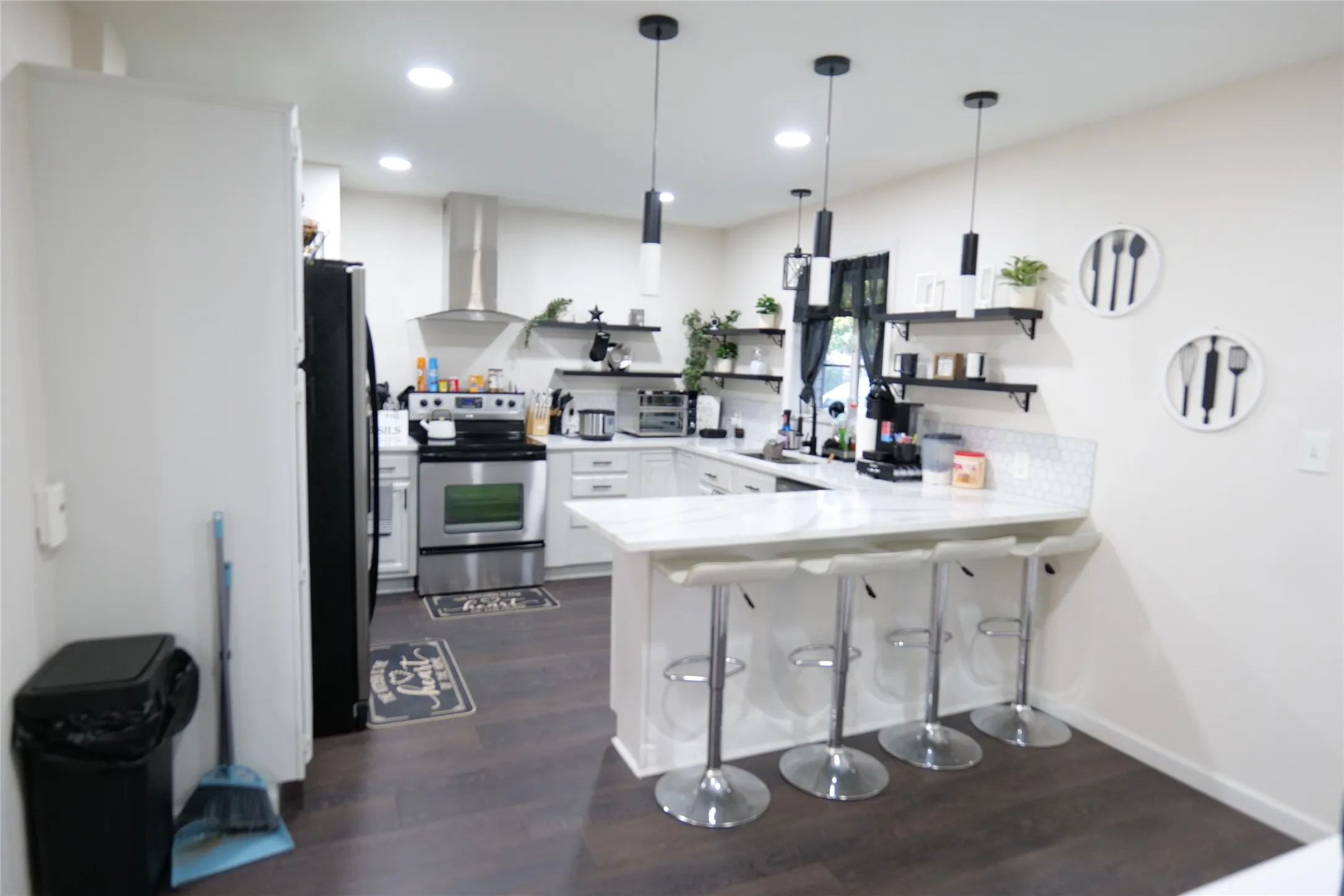 Modern kitchen featuring white cabinetry, dark wood-finish flooring, stainless steel appliances, and an island with bar seating