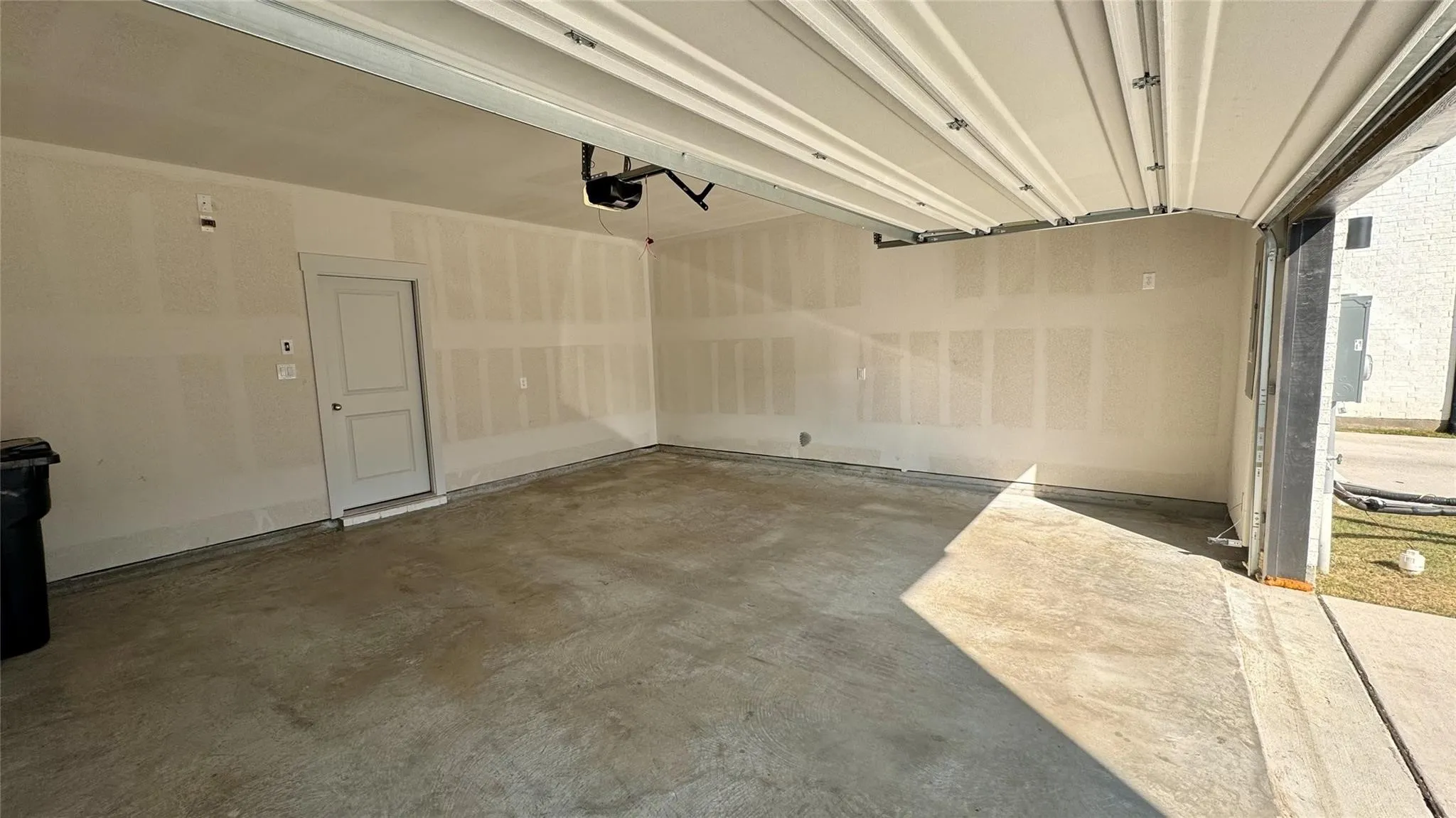 Spacious garage featuring a concrete floor, overhead door, and interior access door