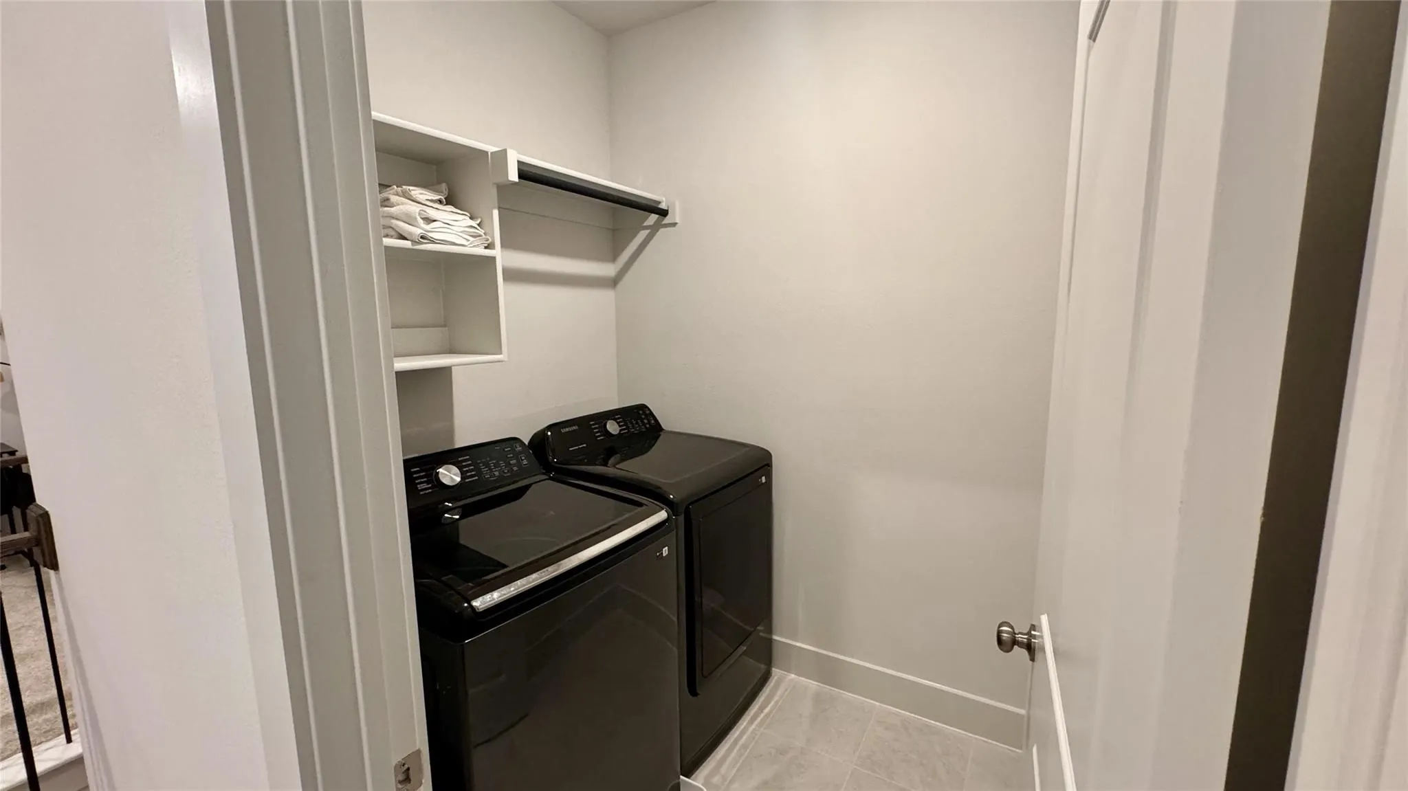 Dedicated laundry area featuring a light gray wall finish and a light-toned tile floor