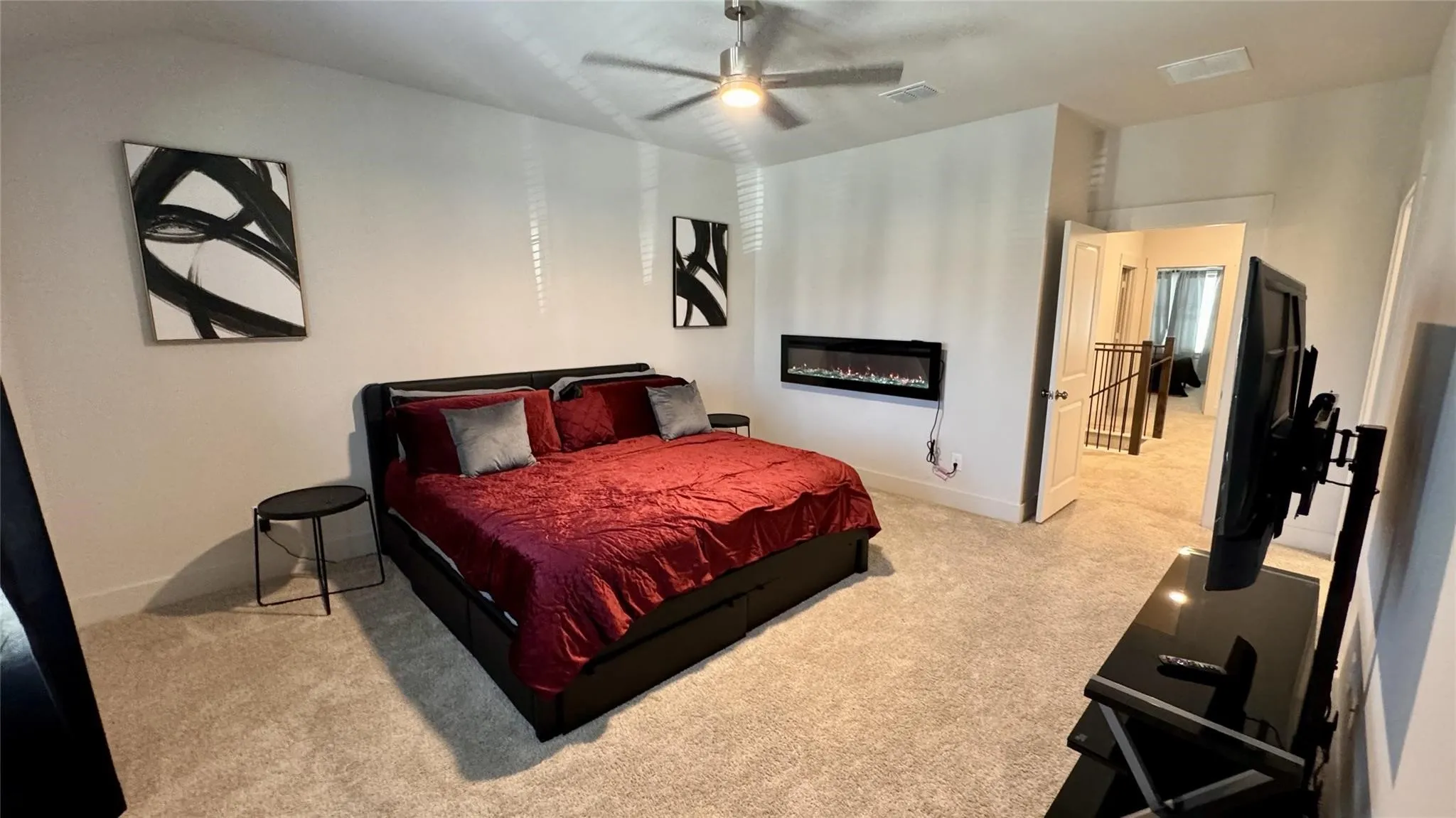 Spacious bedroom featuring plush carpeting, a modern ceiling fan, and an integrated electric fireplace