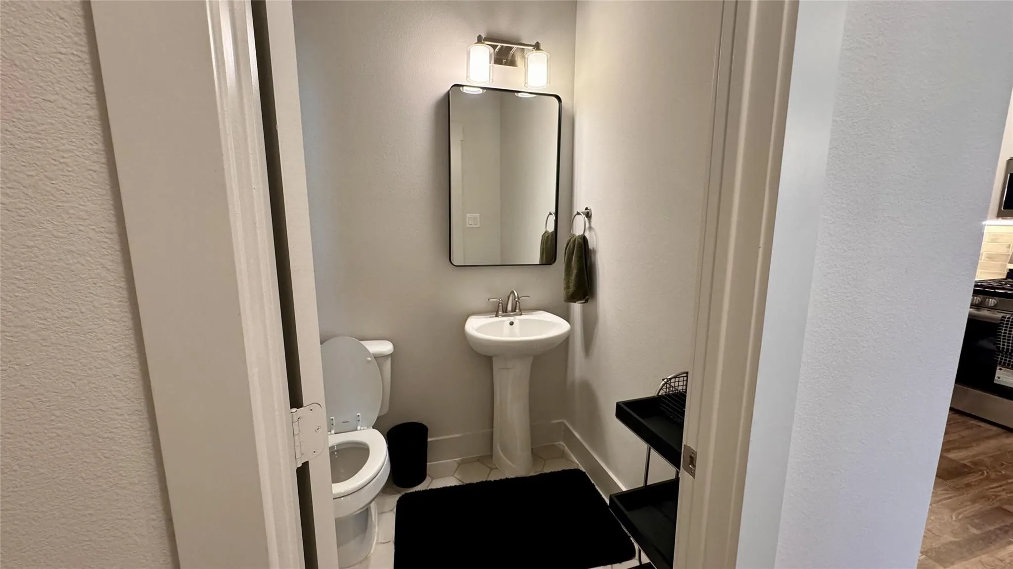 Powder room with a pedestal sink, rectangular mirror, and sconce lighting