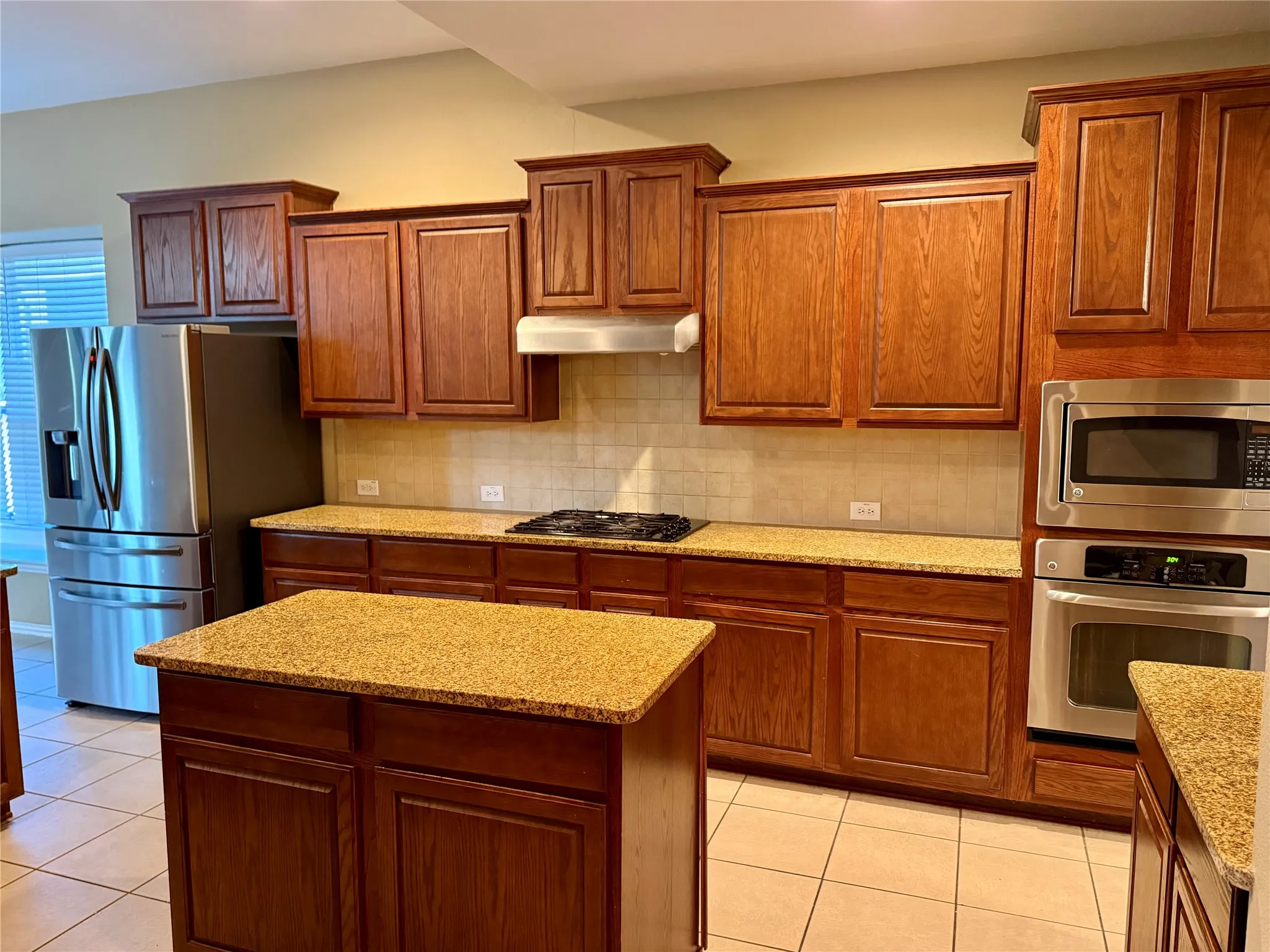 Kitchen featuring wood-finish cabinetry, granite countertops, and tile flooring