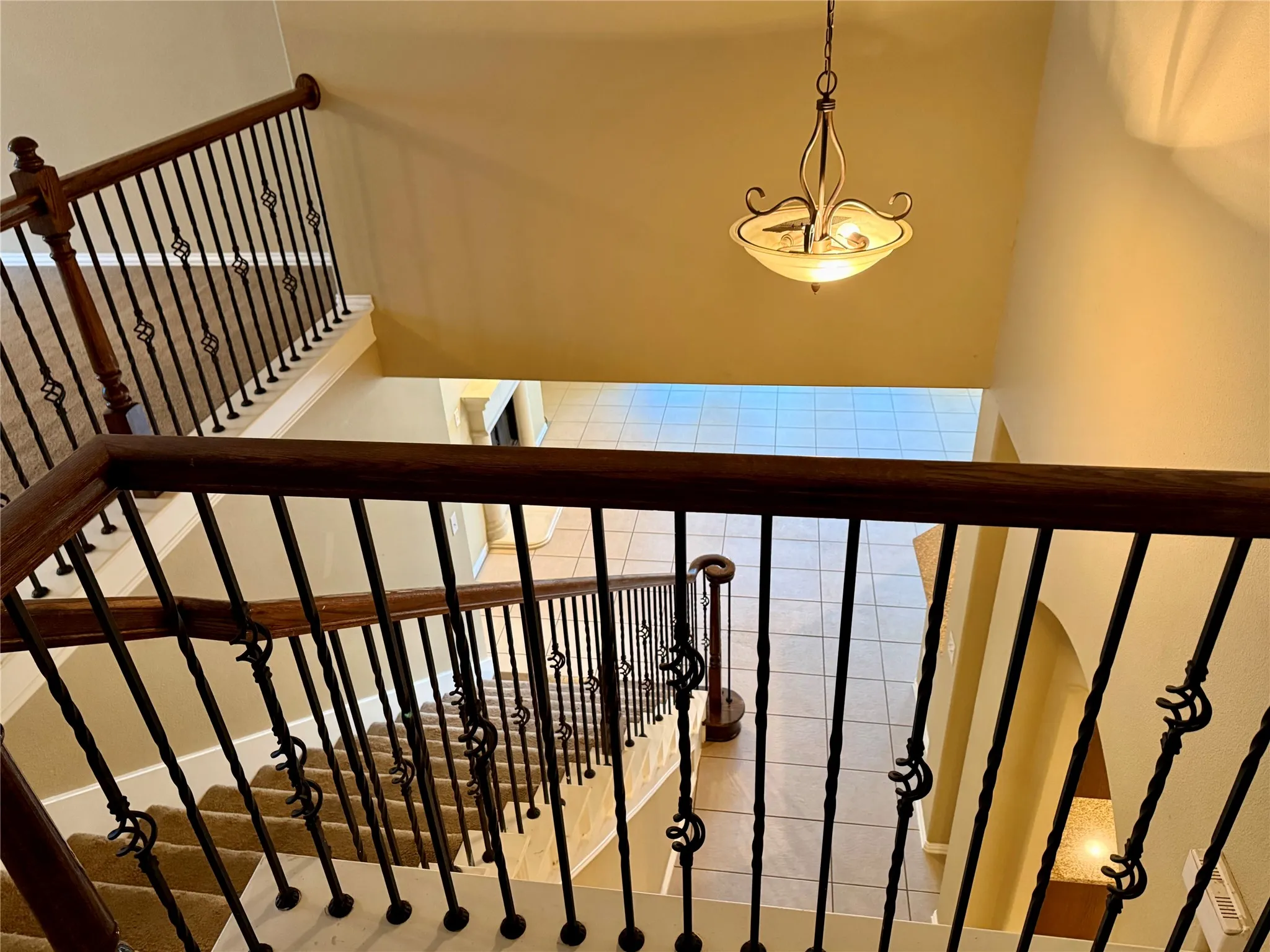 Multi-level interior featuring a grand staircase with wrought iron balusters and dark wood handrails
