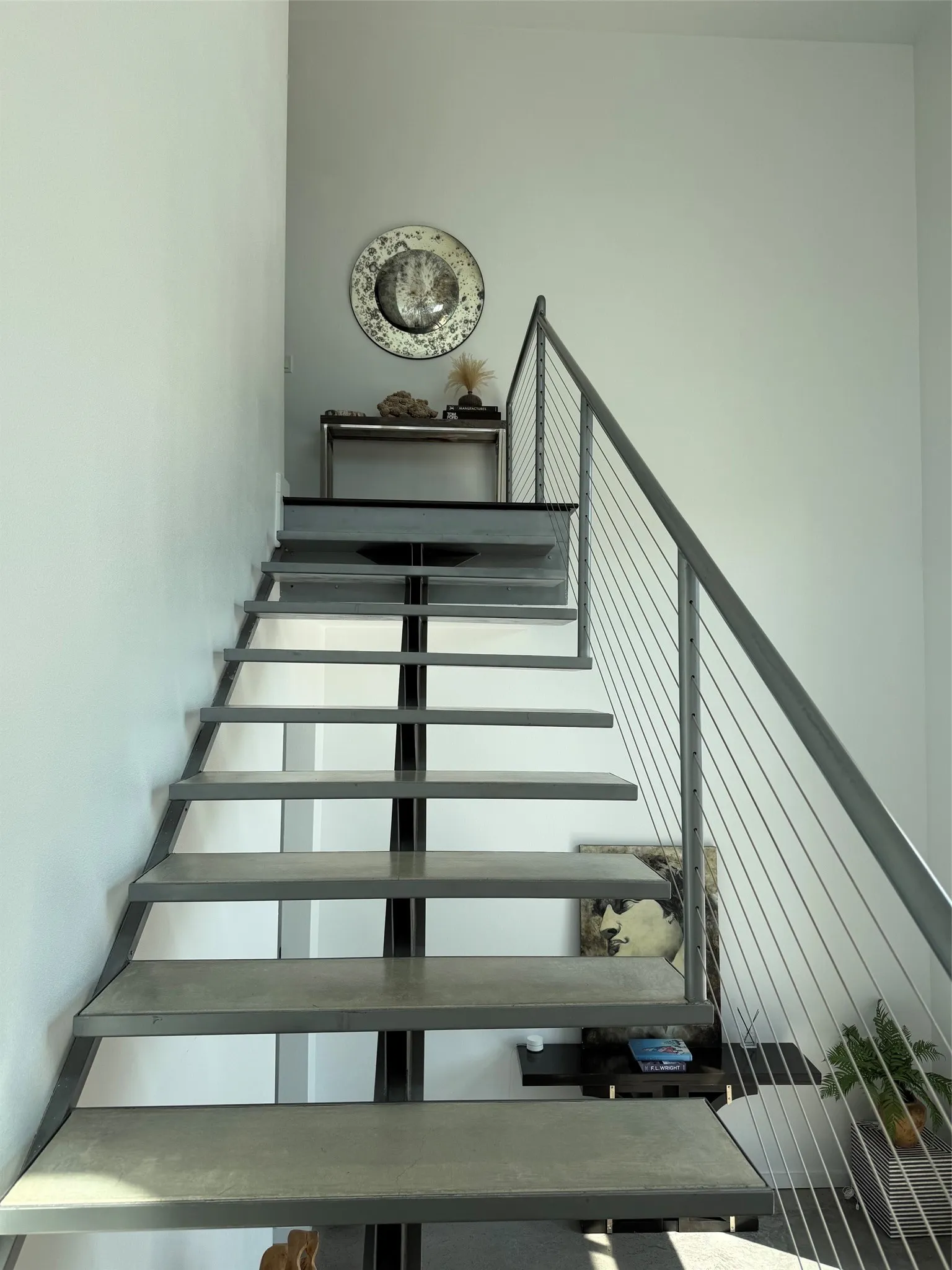 Floating staircase with metal treads, cable railing, and a landing