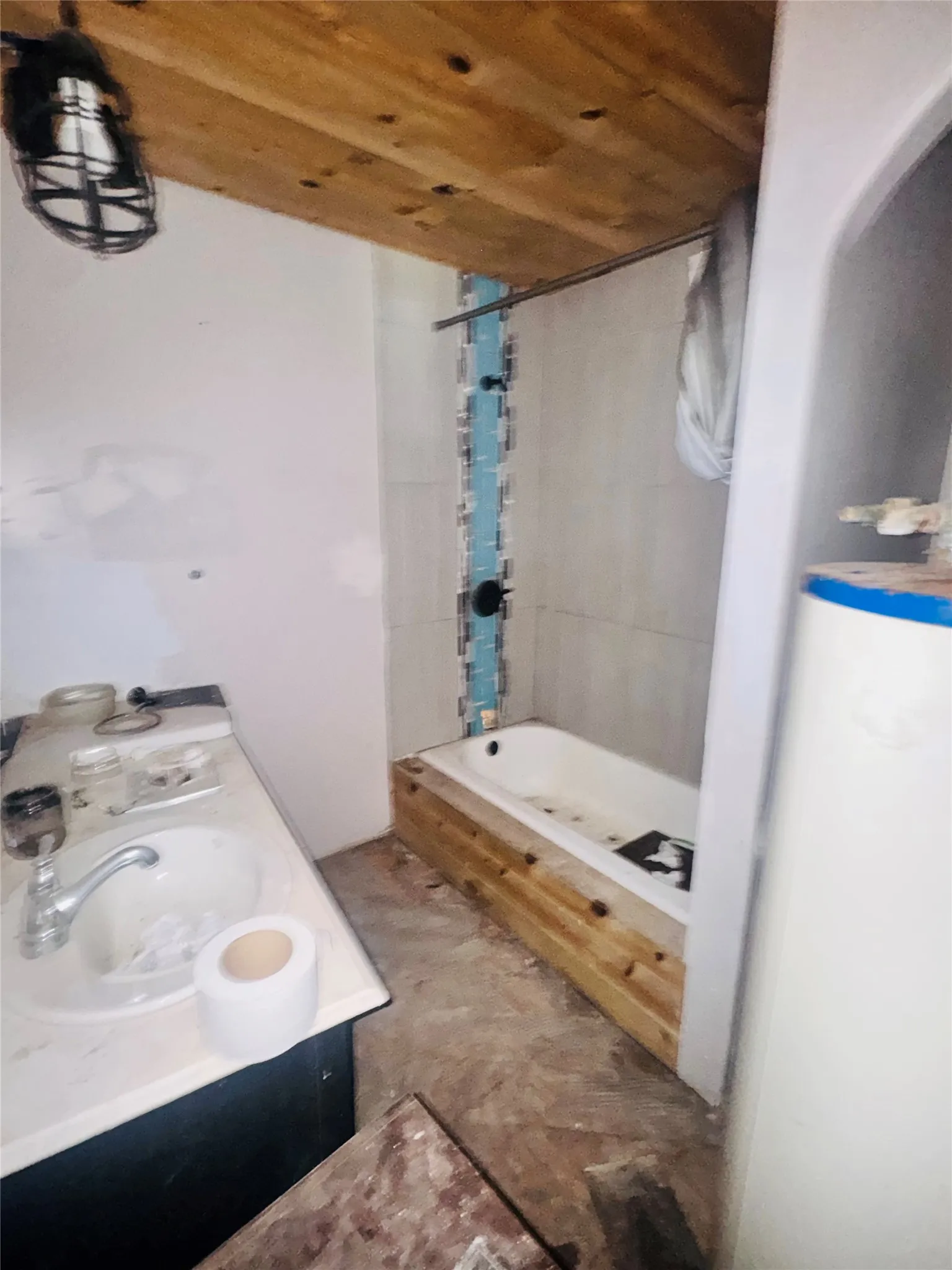 Bathroom featuring a wood plank ceiling, a white bathtub with wood paneling, and a tiled shower surround