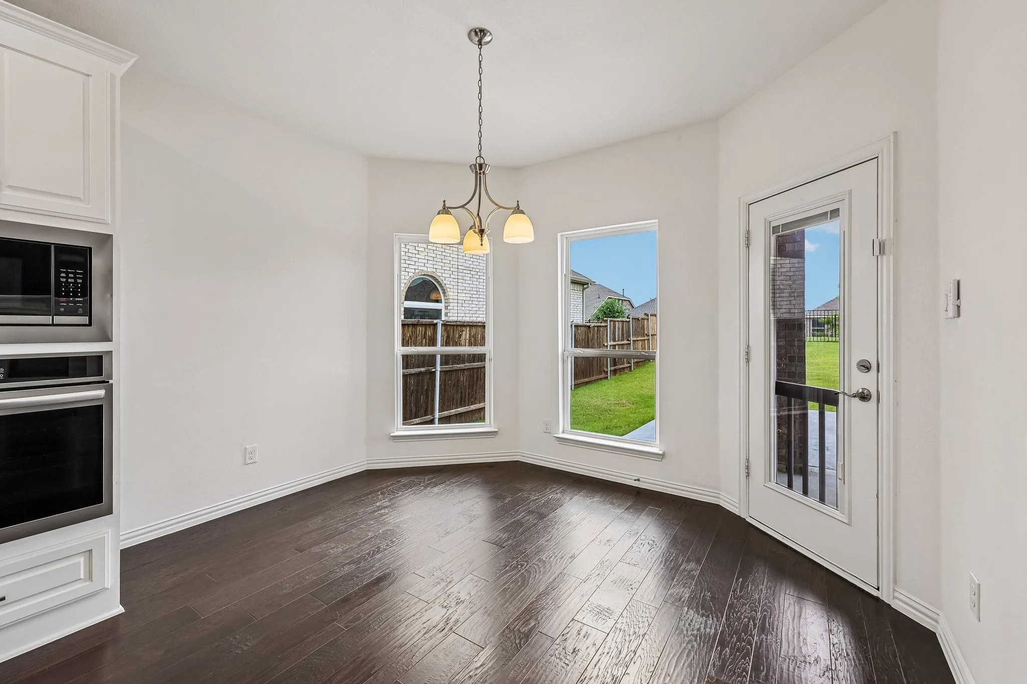 Dining area featuring dark wood-finish flooring, white baseboards, and a three-light chandelier