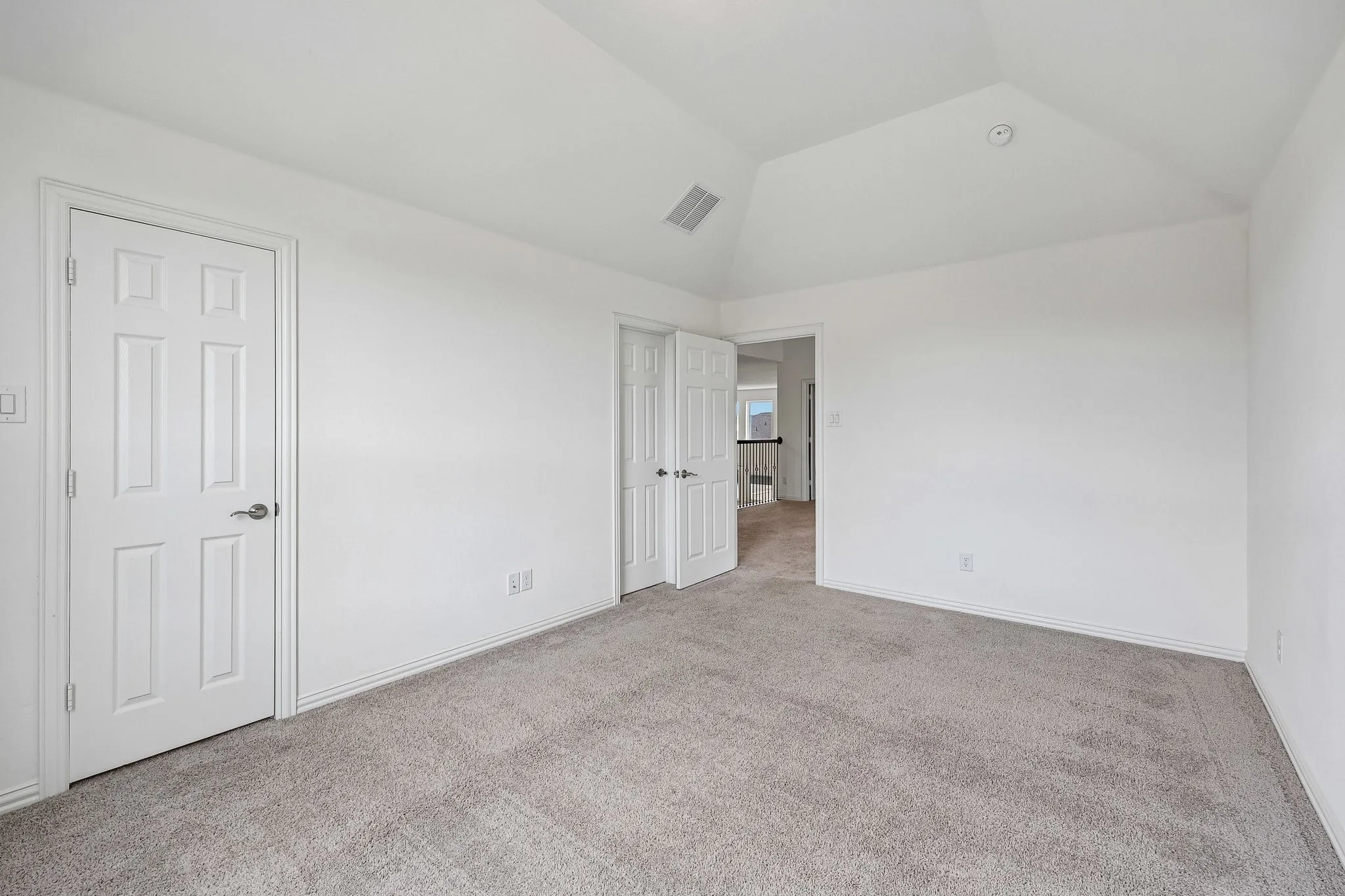 Spacious room featuring vaulted ceilings, light gray carpet, and white trim