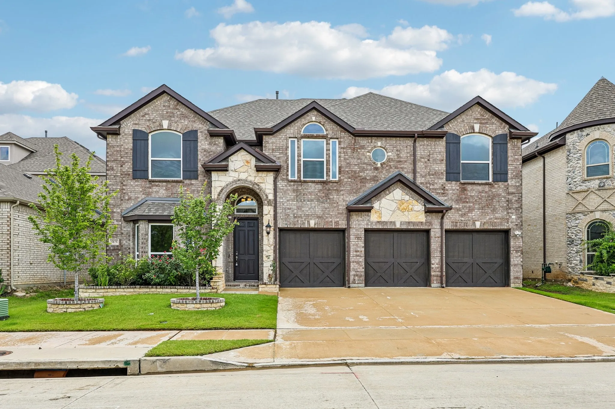 Two-story brick and stone exterior with a three-car garage