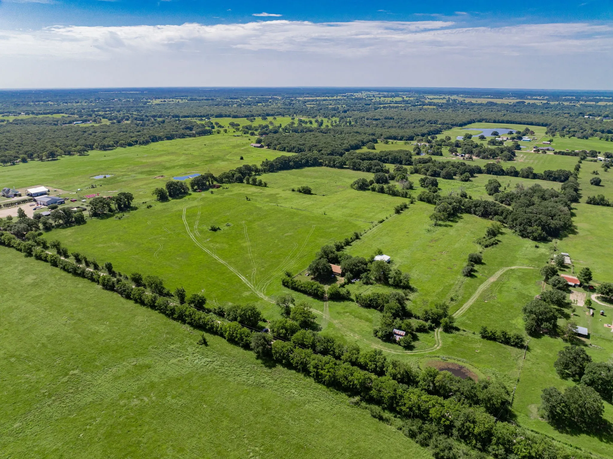 Expansive rural landscape featuring extensive green pastures and mature tree lines