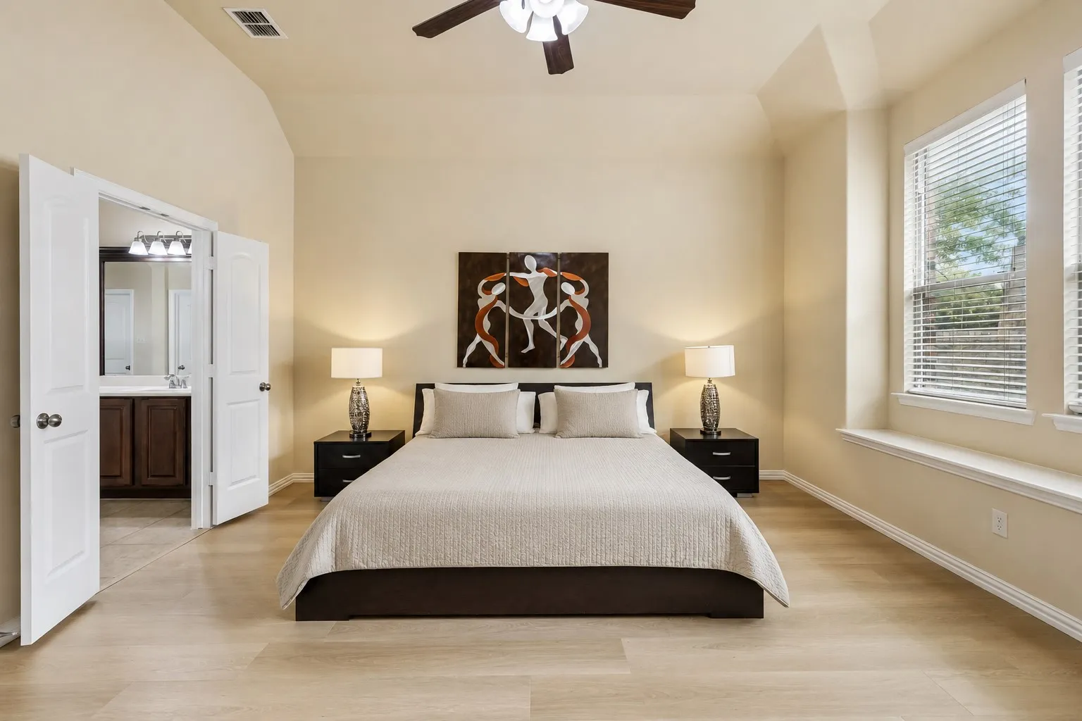 Vaulted ceiling bedroom featuring wood-finish flooring and a ceiling fan