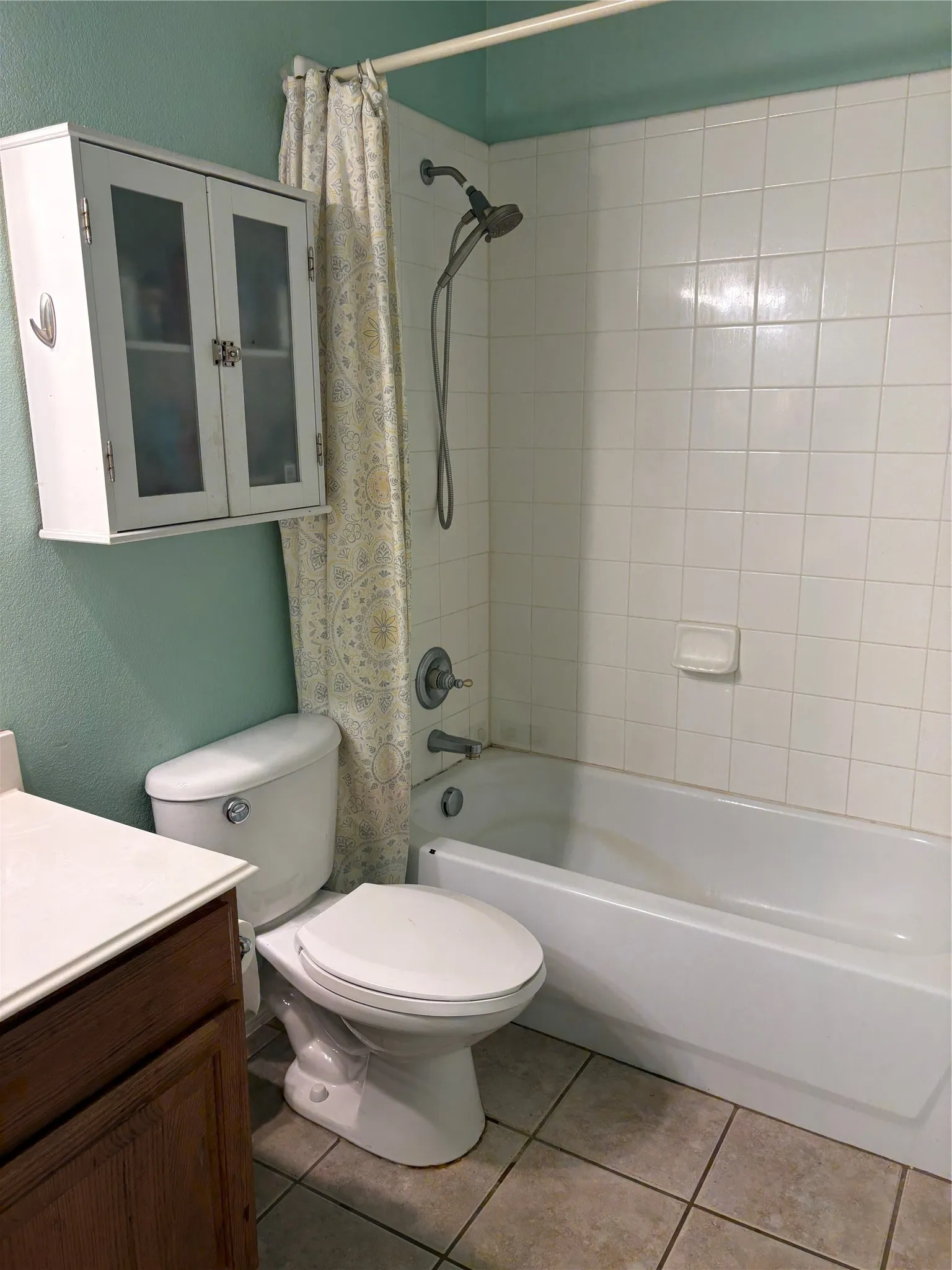 White subway tile shower surround with an adjustable showerhead, white built-in bathtub, and a wall-mounted medicine cabinet