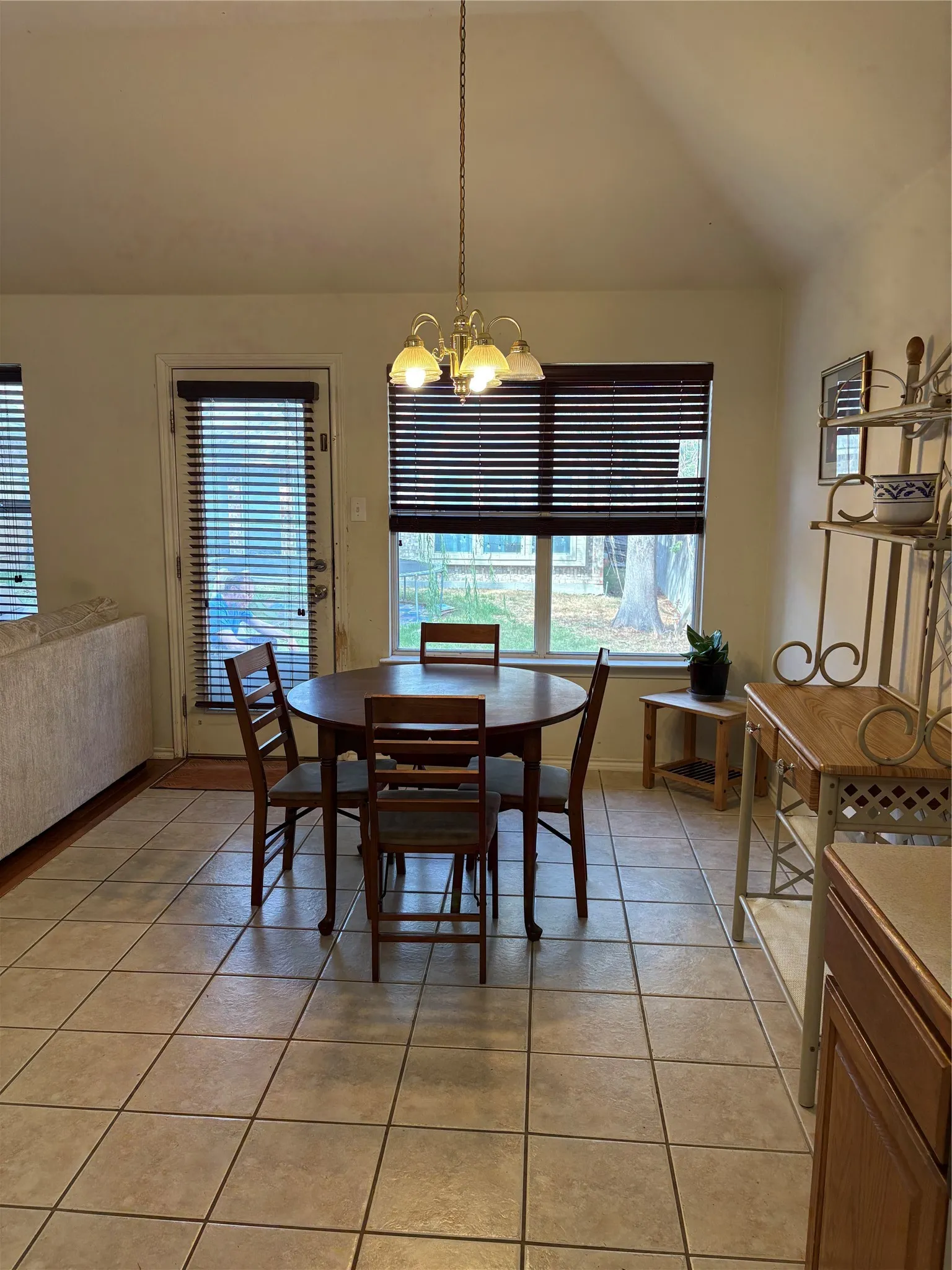 Vaulted ceiling with a chandelier, tile flooring, and a glass-paneled exterior door