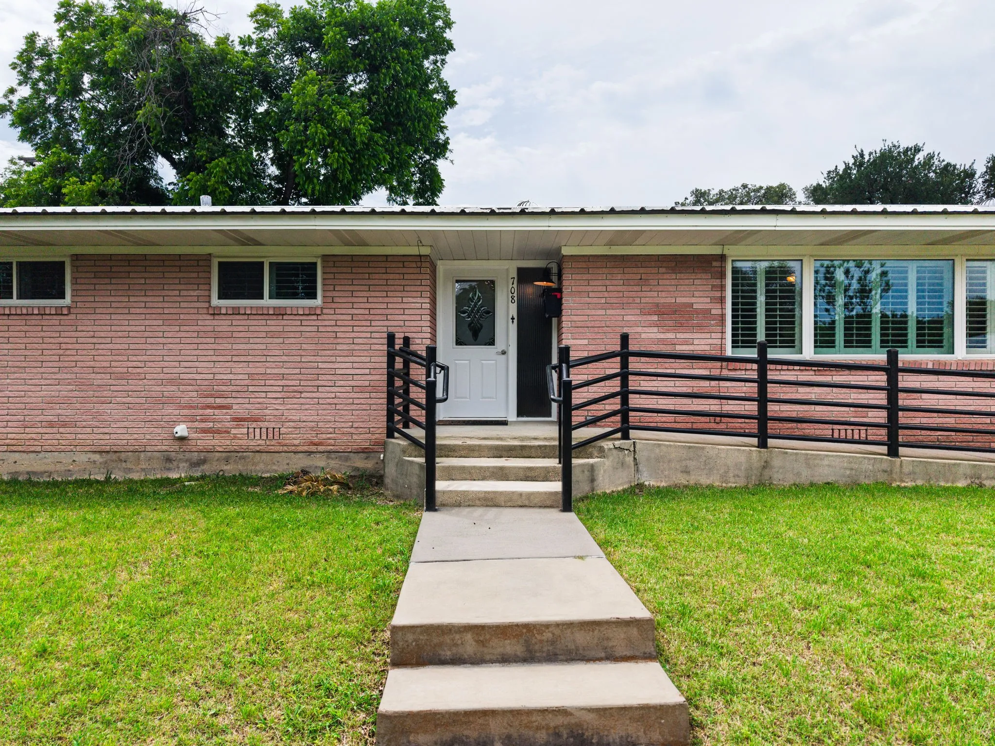 Brick exterior facade featuring a concrete walkway, entry steps, and a white front door with decorative glass