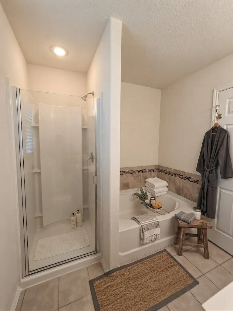 Primary bathroom featuring a frameless glass-enclosed shower with tile surround, pedestal sink, ceramic tile flooring with decorative border accent, recessed ceiling lighting, and ceramic wall tile detailing