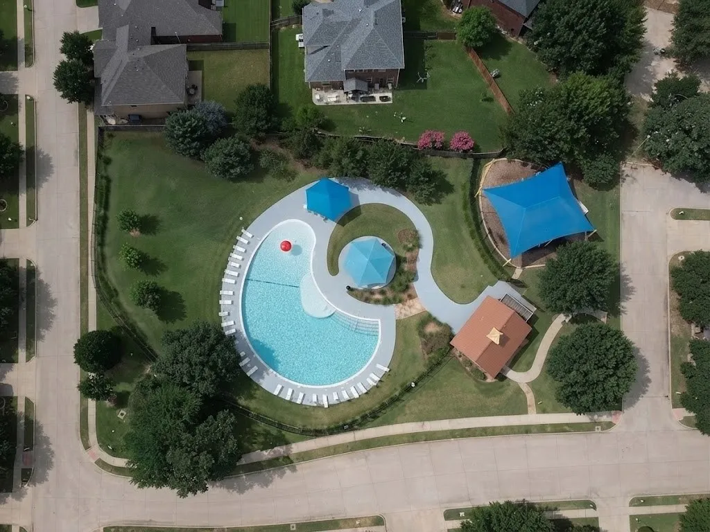 Community pool with extensive lounge seating, an adjacent shade structure, and a dedicated structure with a hip roof