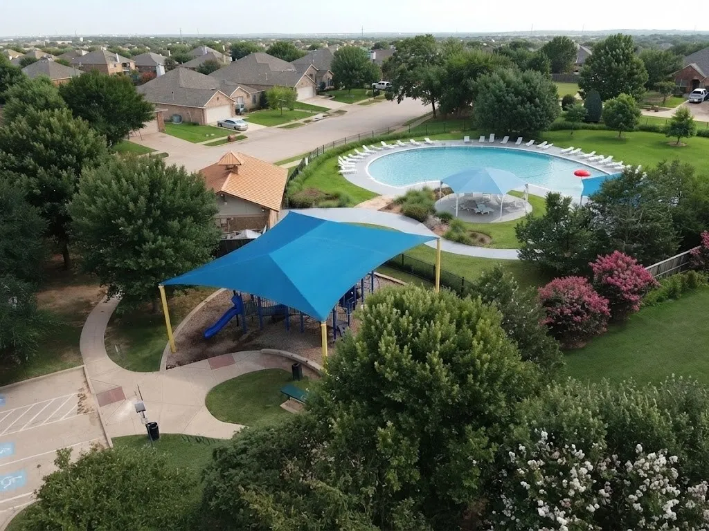 Circular community swimming pool with shade structures, surrounded by green landscaping