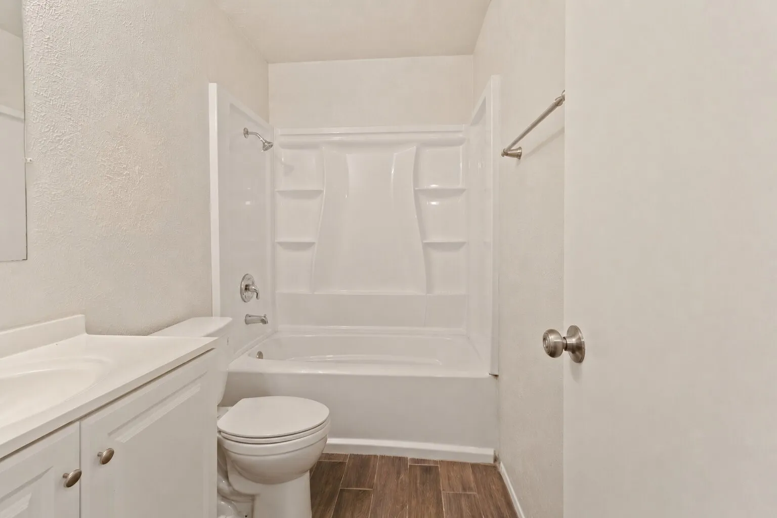 Bathroom featuring a white vanity with integrated sink, white cabinetry, toilet, and a white shower/tub combination unit