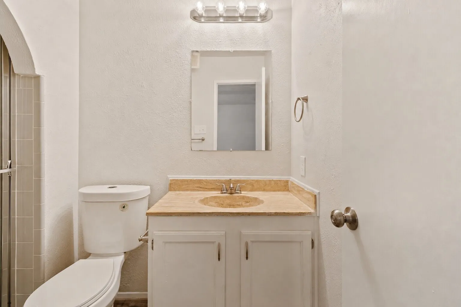 Bathroom vanity featuring a vessel sink, light-toned countertop, and white cabinetry