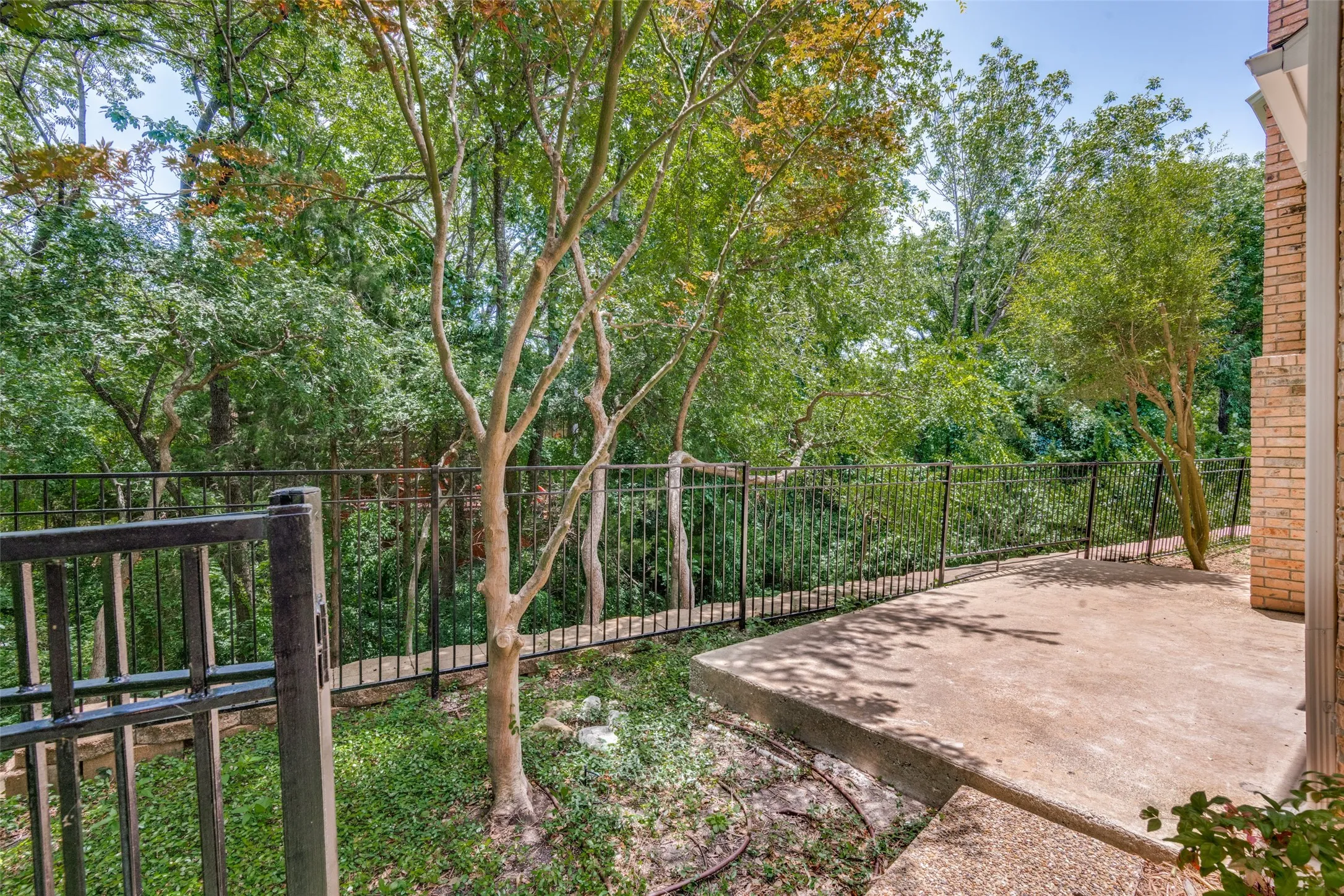Private patio area featuring a concrete surface and black metal fencing