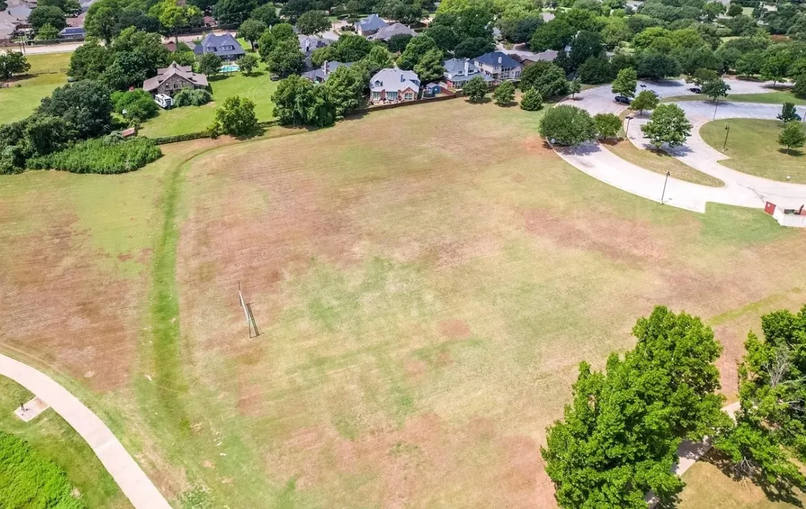Expansive green space featuring a paved walking path and mature trees
