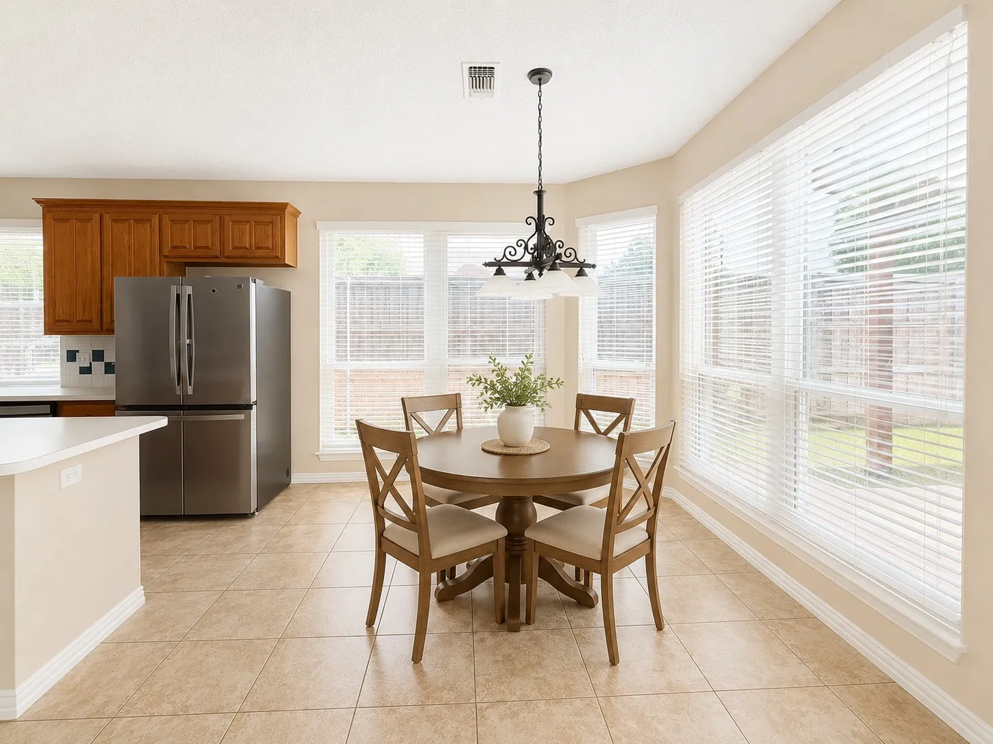 Tile flooring, multiple windows, built-in cabinetry, stainless steel refrigerator, and a decorative chandelier