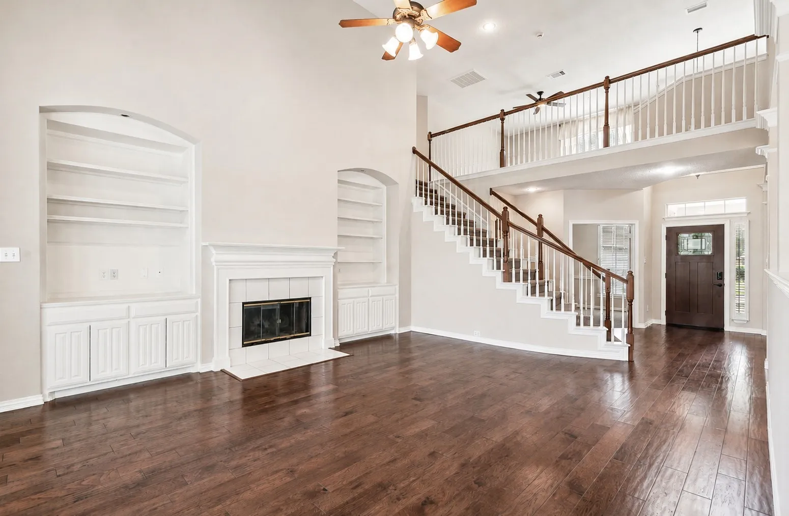 Vaulted ceiling, ceiling fan, wood-finish flooring, fireplace with tiled surround, built-in shelving and cabinetry