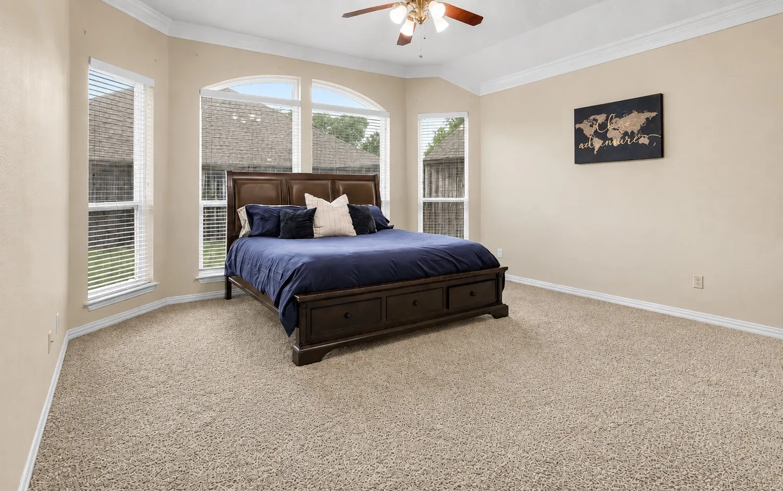 Bay window with arched transom, ceiling fan, and crown molding