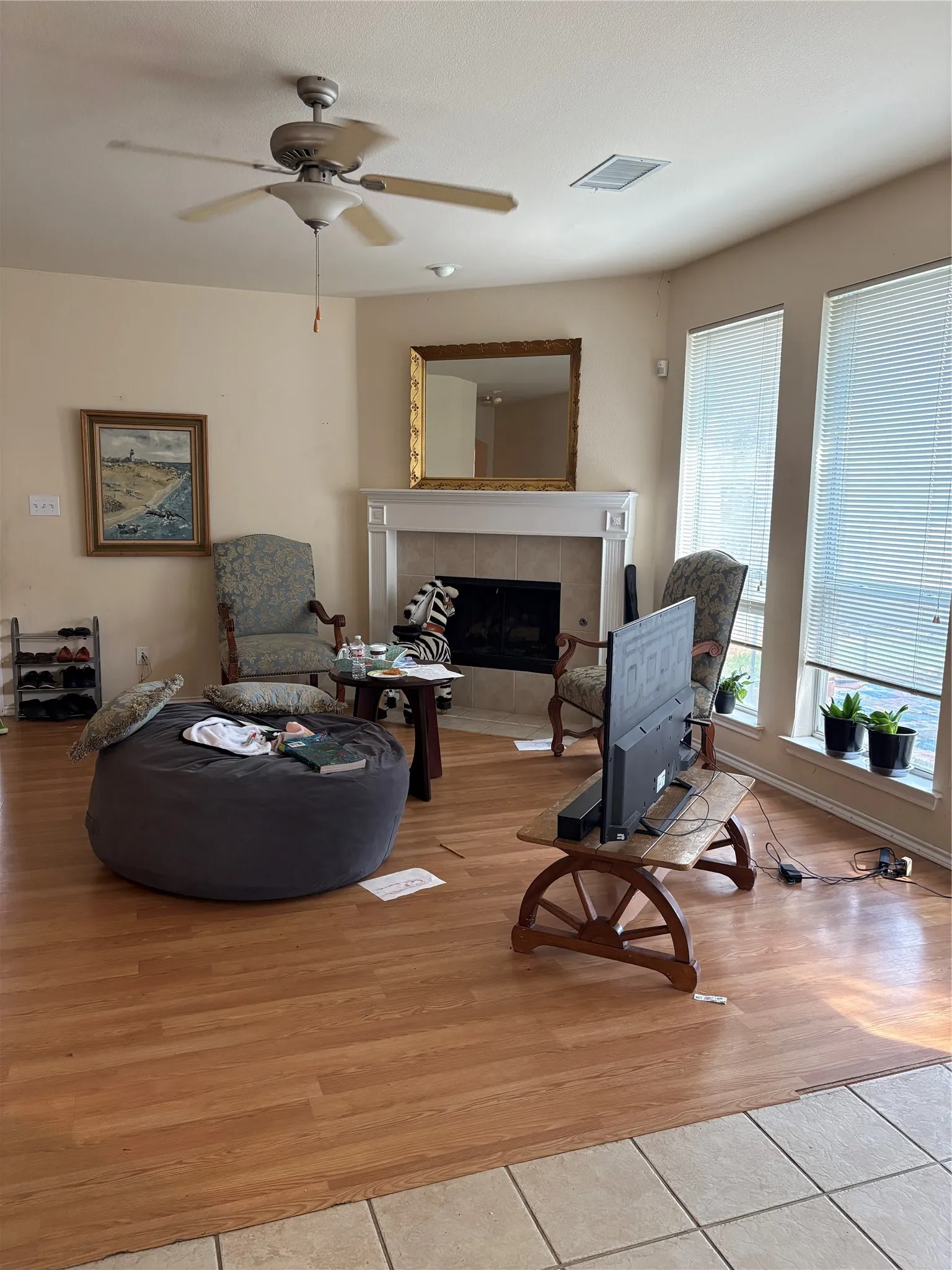Living area featuring wood-finish flooring, a fireplace with a white mantel, and ceiling fan