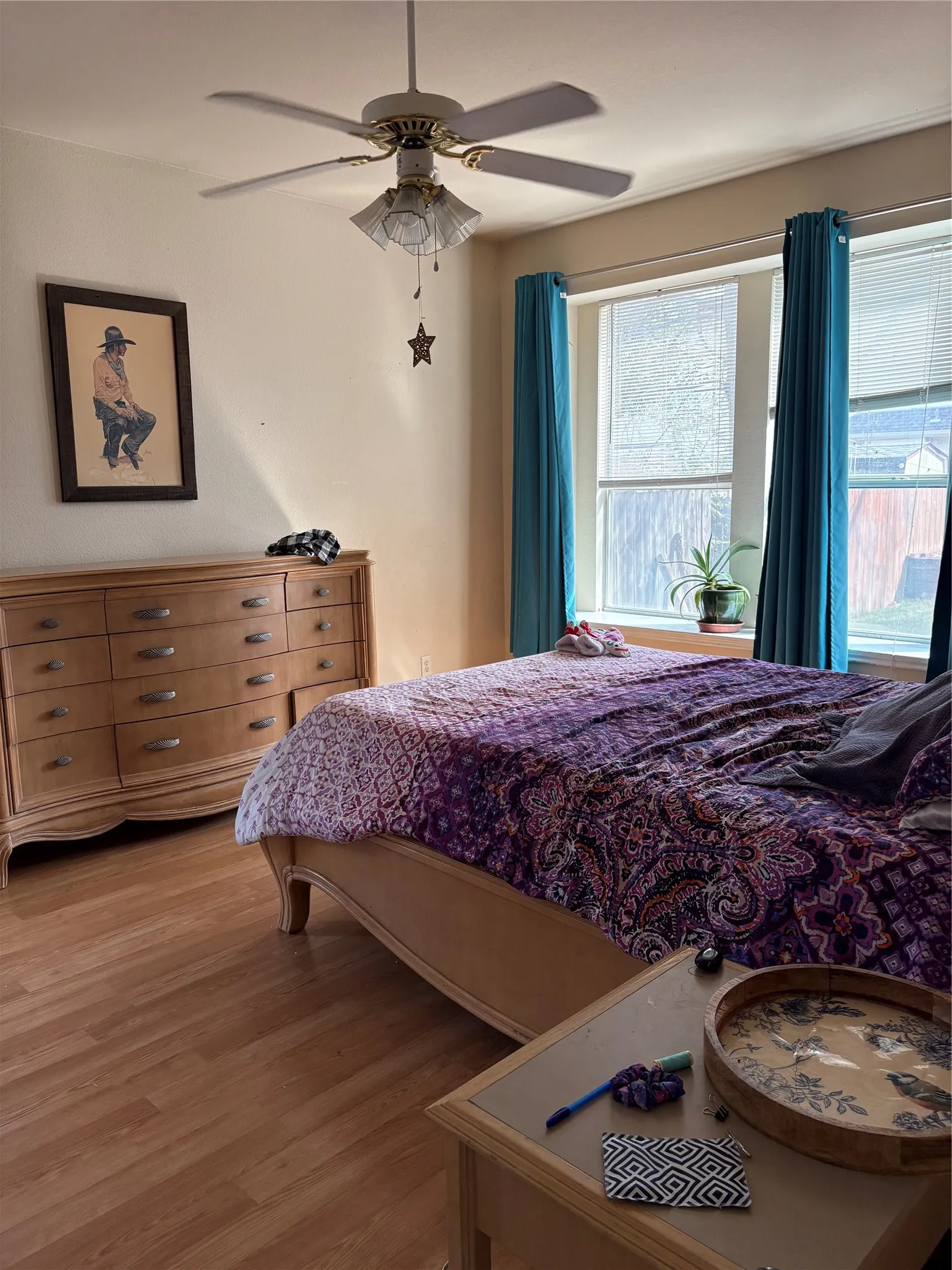 Wood-finish flooring, ceiling fan with integrated lighting, and multiple windows with blinds
