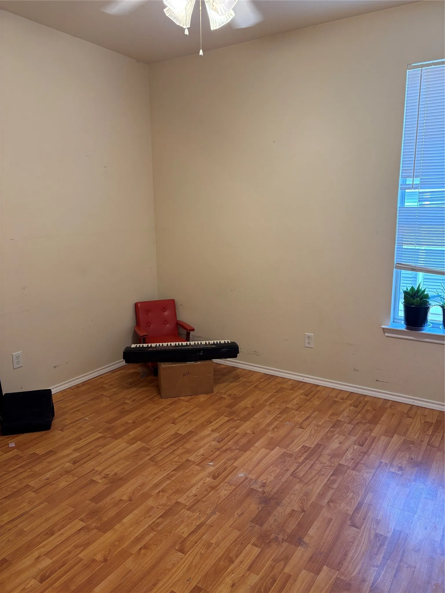 Wood-finish flooring with white trim and a ceiling fan