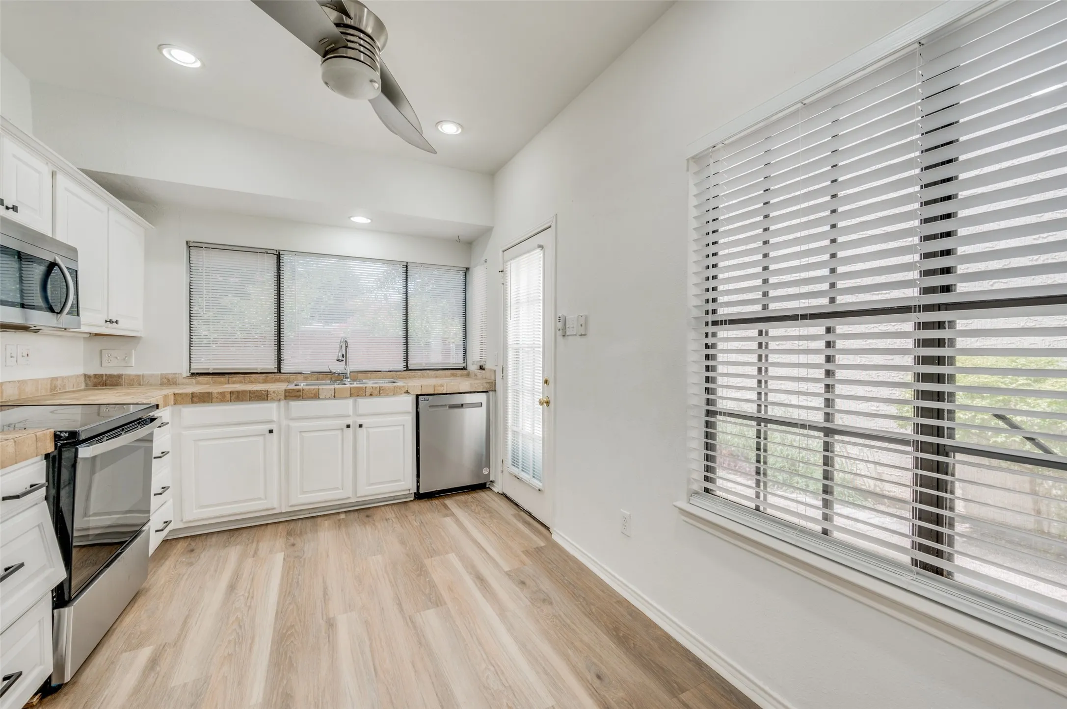 Kitchen featuring wood-finish flooring, white cabinetry, stainless steel appliances, and recessed lighting