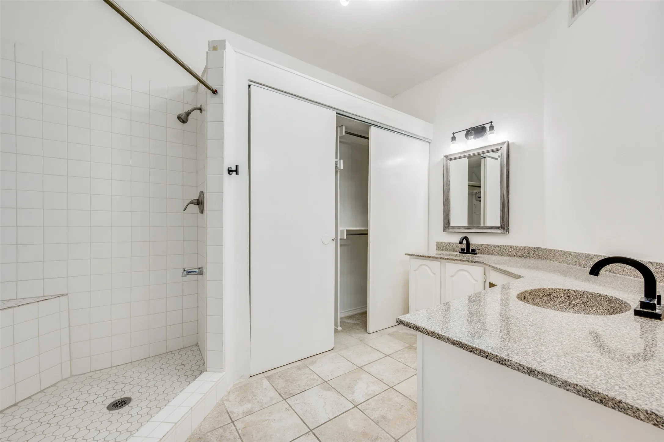 Bathroom featuring a walk-in shower with white subway tile, a built-in shower bench, and a hexagonal tile floor