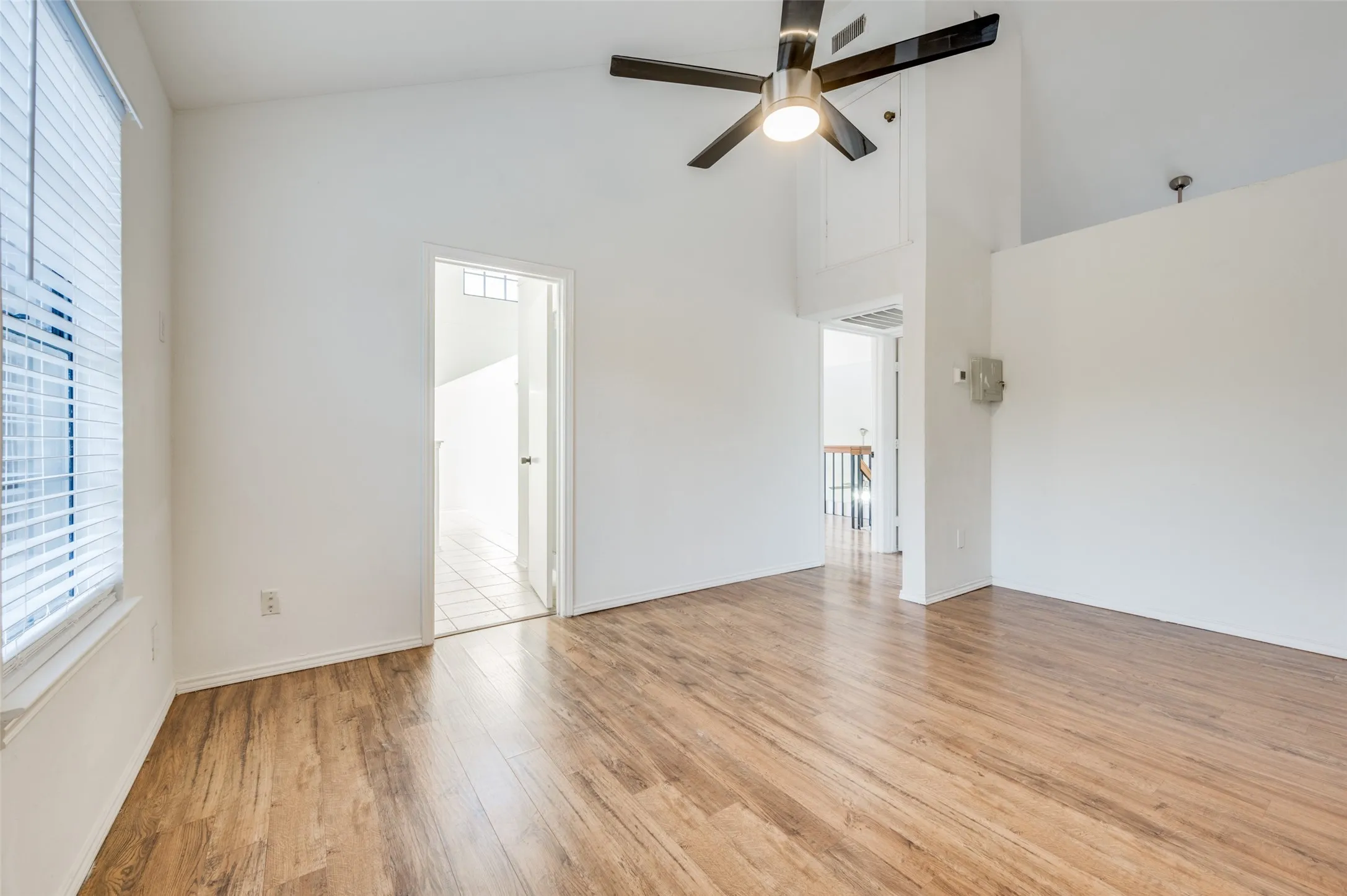 Vaulted ceilings featuring a ceiling fan, wood-finish flooring, and white window blinds