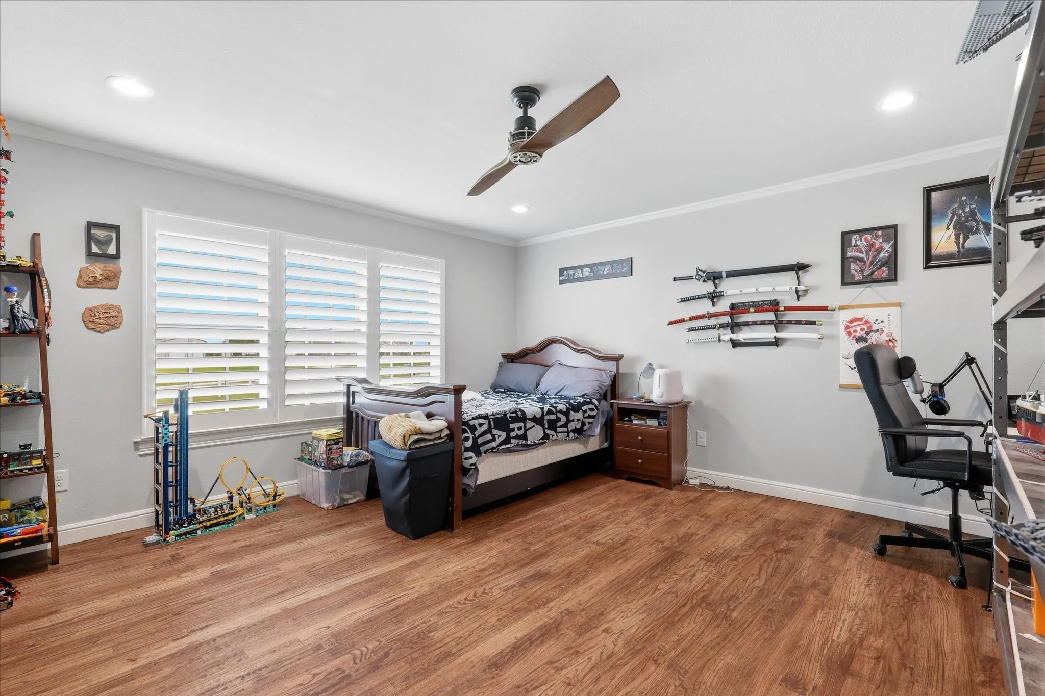 Spacious room featuring wood-finish flooring, white plantation shutters, a ceiling fan, recessed lighting, and crown molding