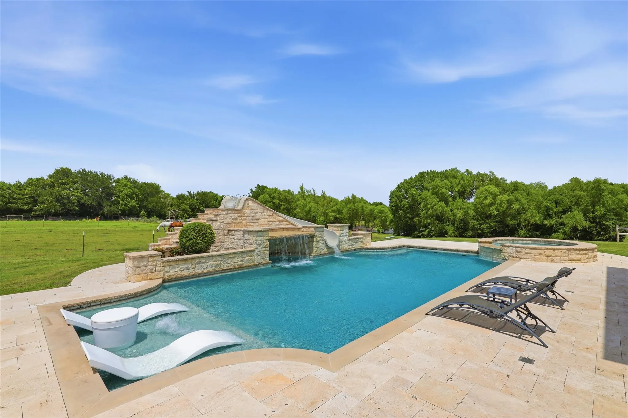 Rectangular pool featuring a rock waterfall, integrated slide, and raised spa