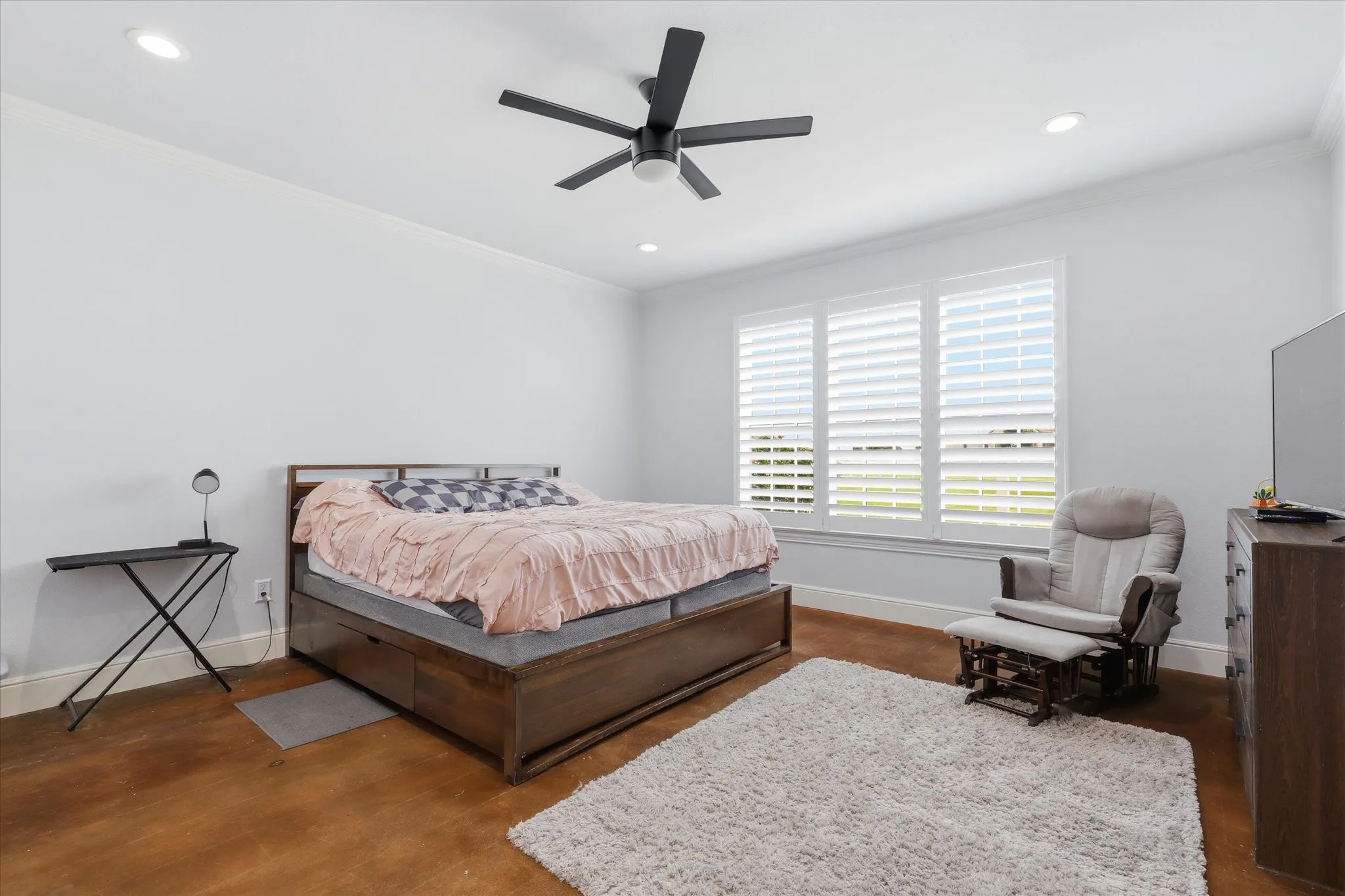 Expansive bedroom featuring warm-toned flooring and white walls