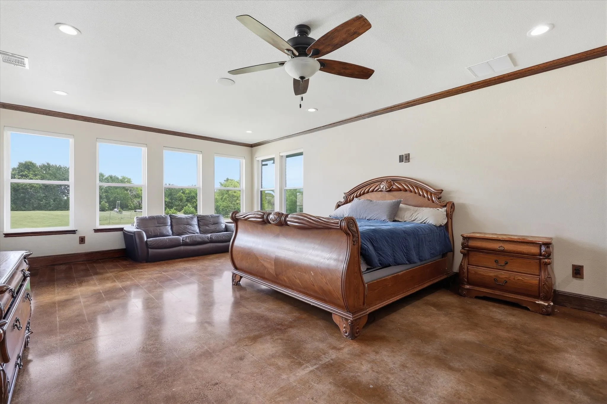 Spacious room featuring multiple large windows, wood-finish flooring, recessed lighting, and a ceiling fan