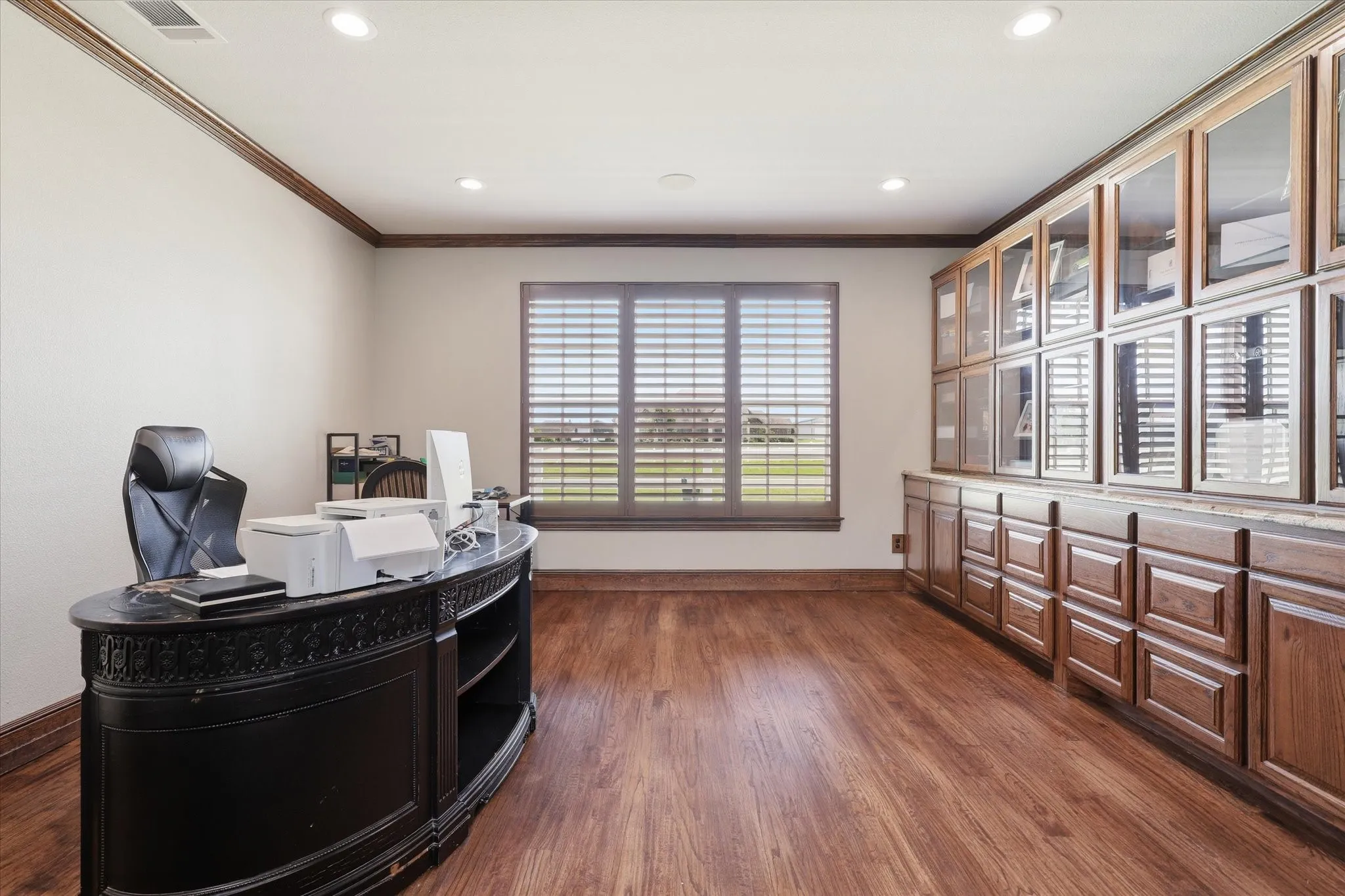 Room featuring rich wood-finish flooring, recessed lighting, and a large window with louvered blinds
