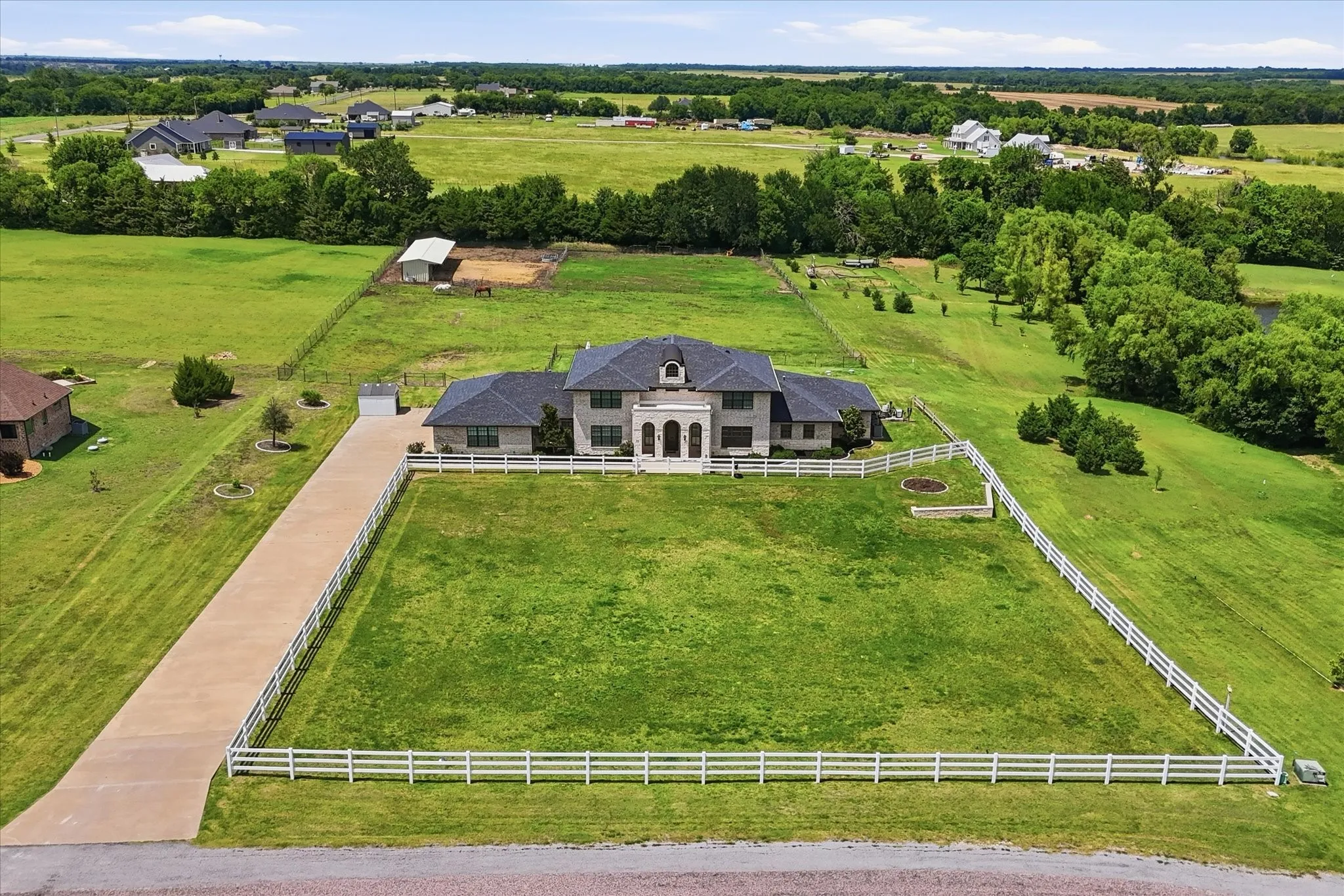 Estate property featuring a two-story residence with a columned portico, a long driveway, and extensive green space