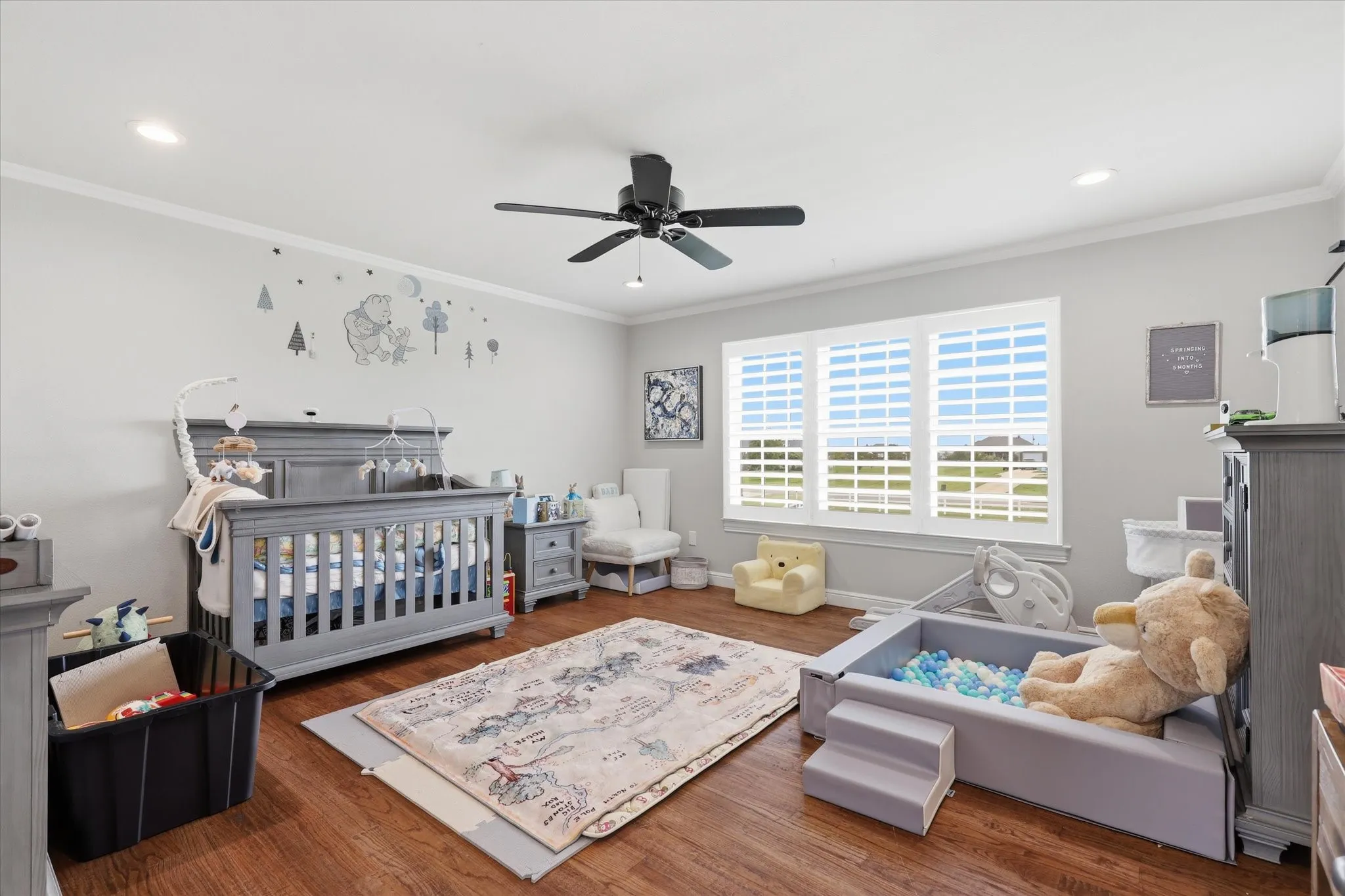 Spacious room featuring wood-finish flooring, light grey wall paint, and white trim