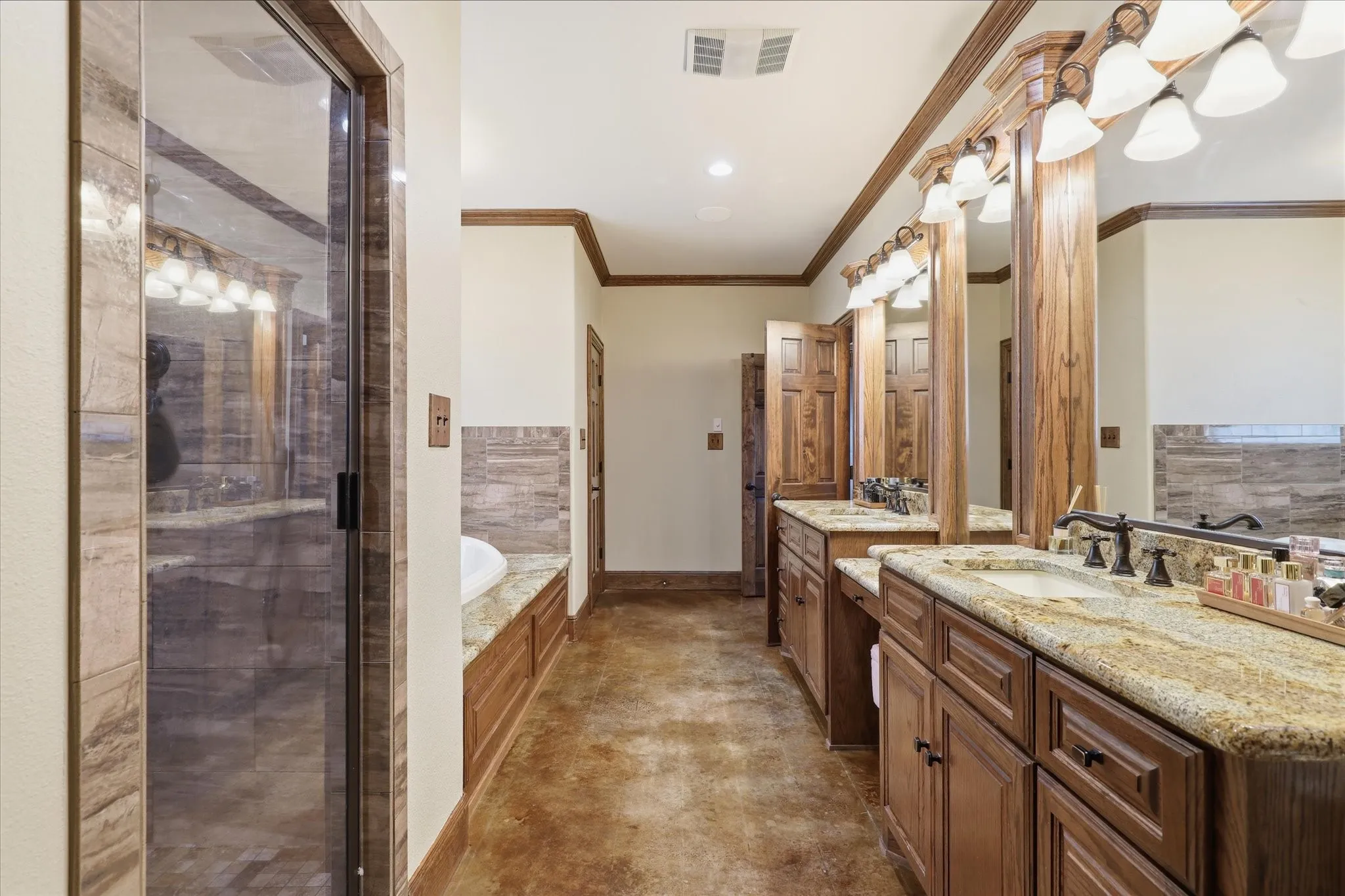 Spacious bathroom featuring dual wood vanities with granite countertops, undermount sinks, and matte black fixtures