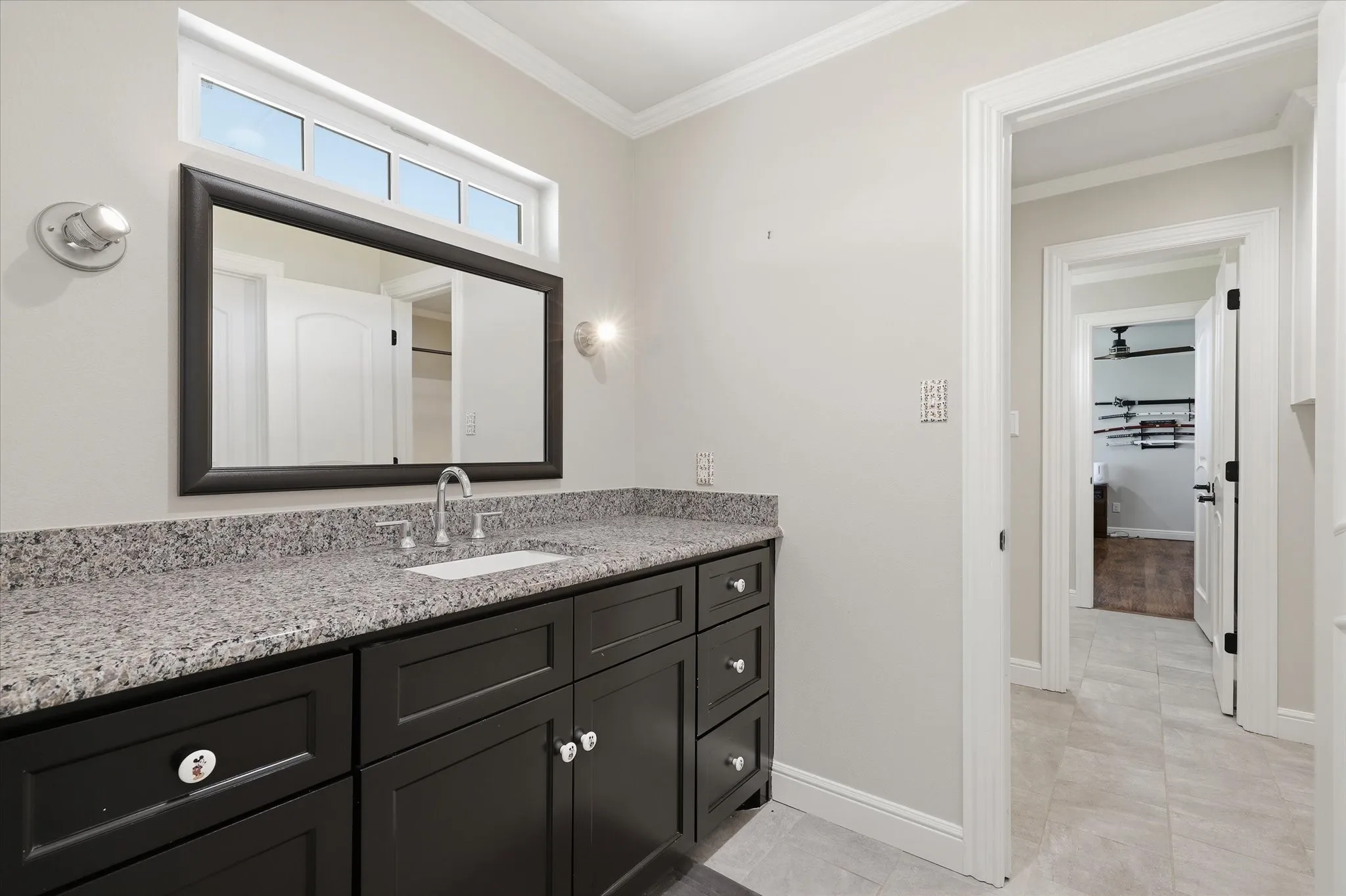 Vanity area featuring a dark wood-finish cabinet, speckled countertop, and an undermount sink
