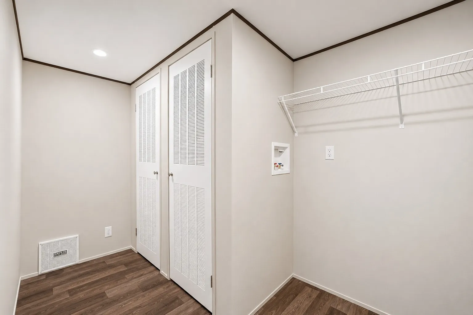 Dedicated utility area featuring wood-finish flooring, bright recessed lighting, white louvered bifold doors, and a wire shelving system