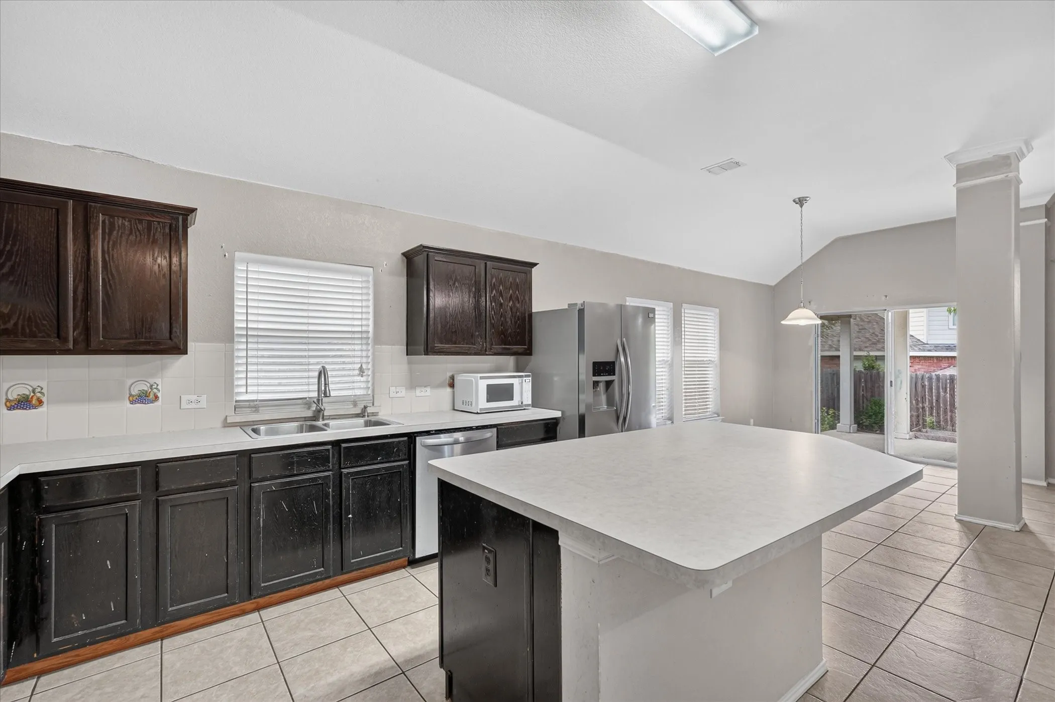 Kitchen featuring dark wood cabinetry, light countertops, and tile flooring