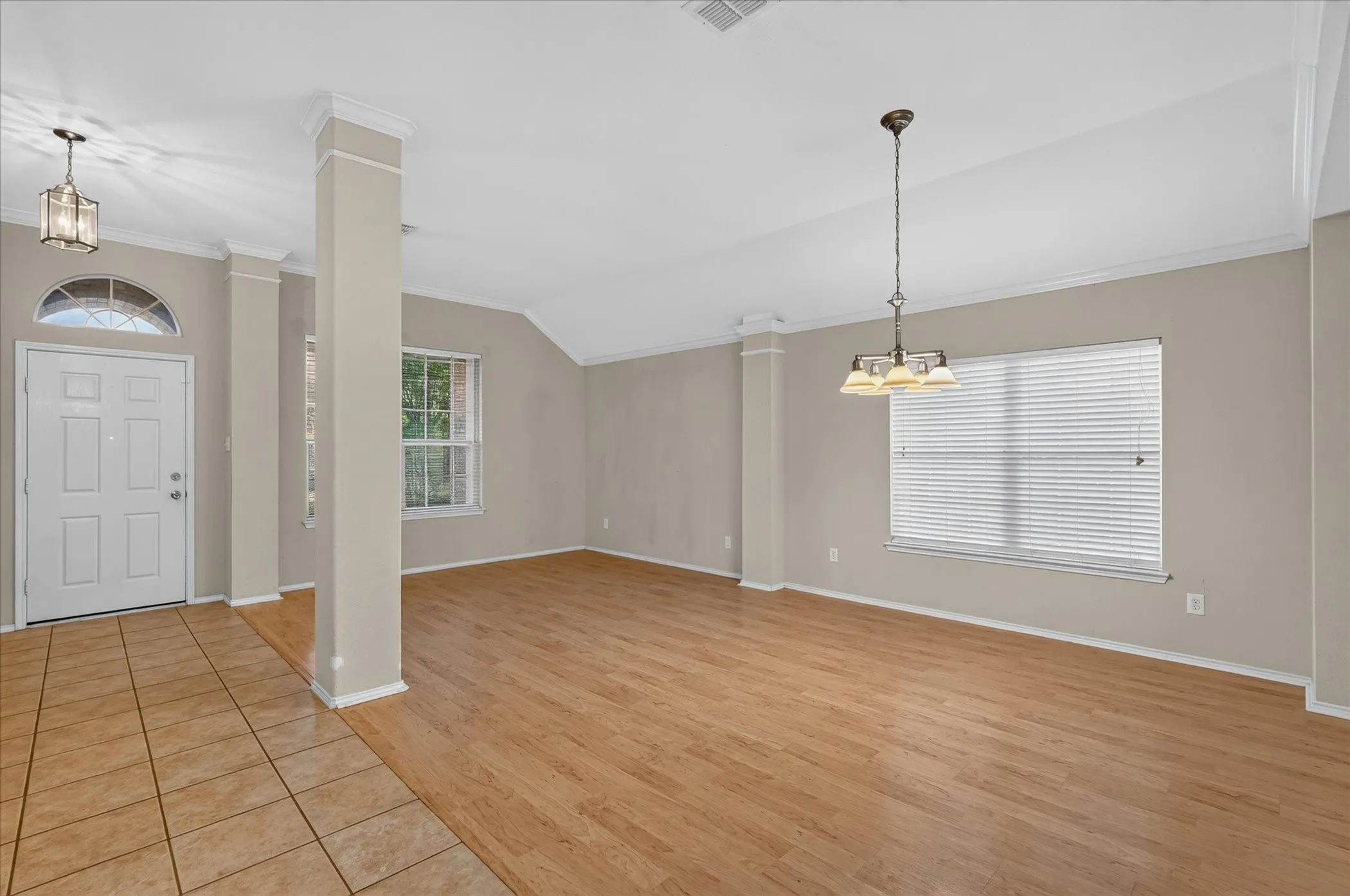 Entryway and open concept living space featuring a white paneled door with an arched transom, tile flooring, wood-finish flooring, a decorative chandelier, and recessed lighting