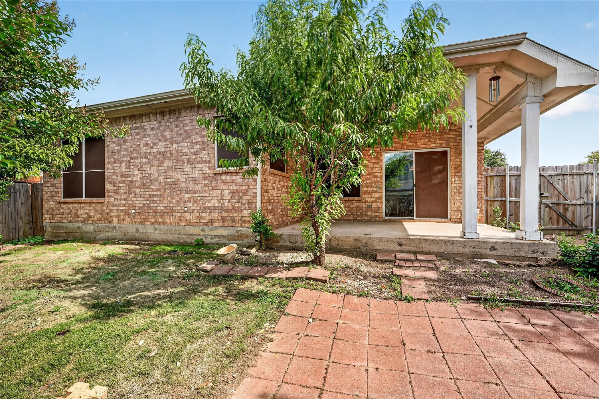 Brick exterior with a covered patio, concrete slab, and sliding glass door access