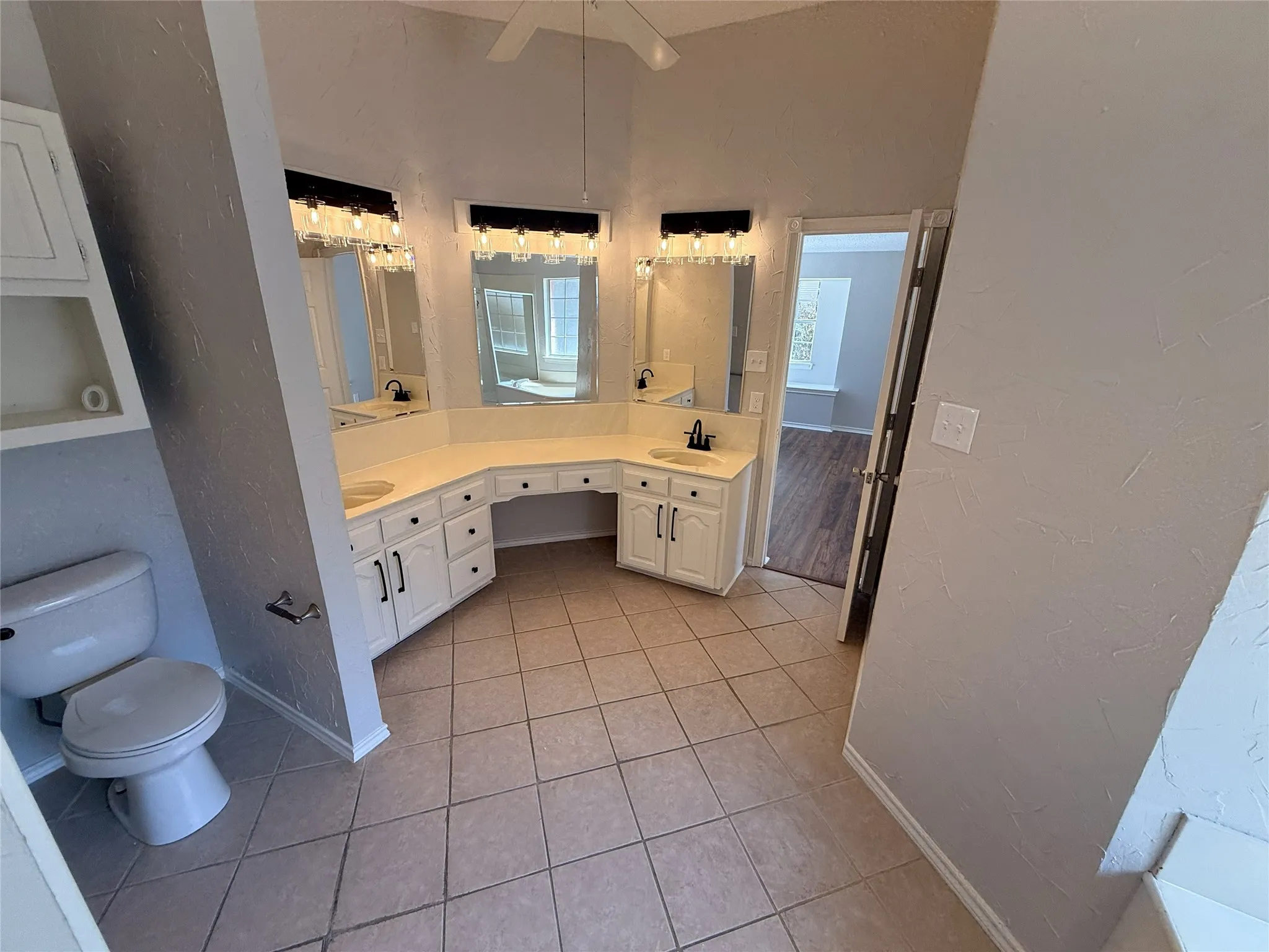Double vanity with integrated sinks, white cabinetry, tile flooring, and vaulted ceiling