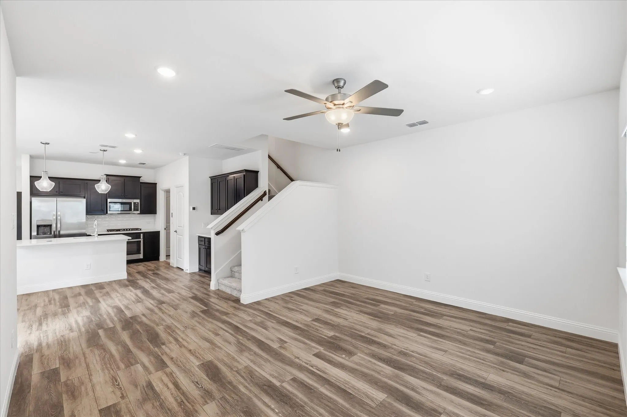Open-concept living space featuring gleaming wood-finish flooring, recessed ceiling lighting, and a ceiling fan with integrated light​​‌​​​​‌​​‌‌​‌‌​​​‌‌​‌​‌​‌​​​‌​​ fixture
