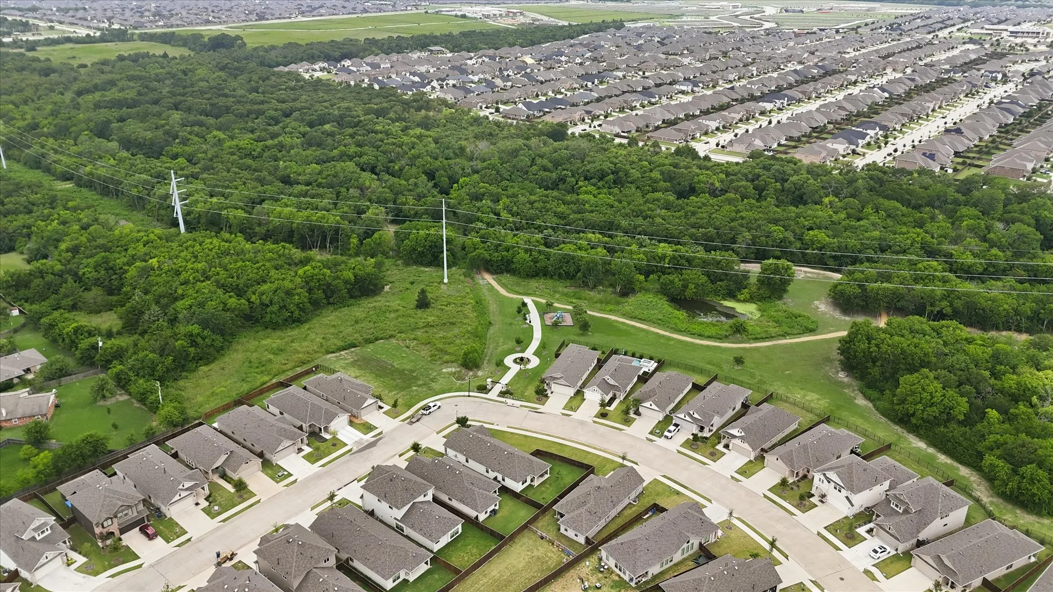 Newly developed residential community featuring tree-lined streets, manicured lawns, and contemporary single-family homes with attached garages