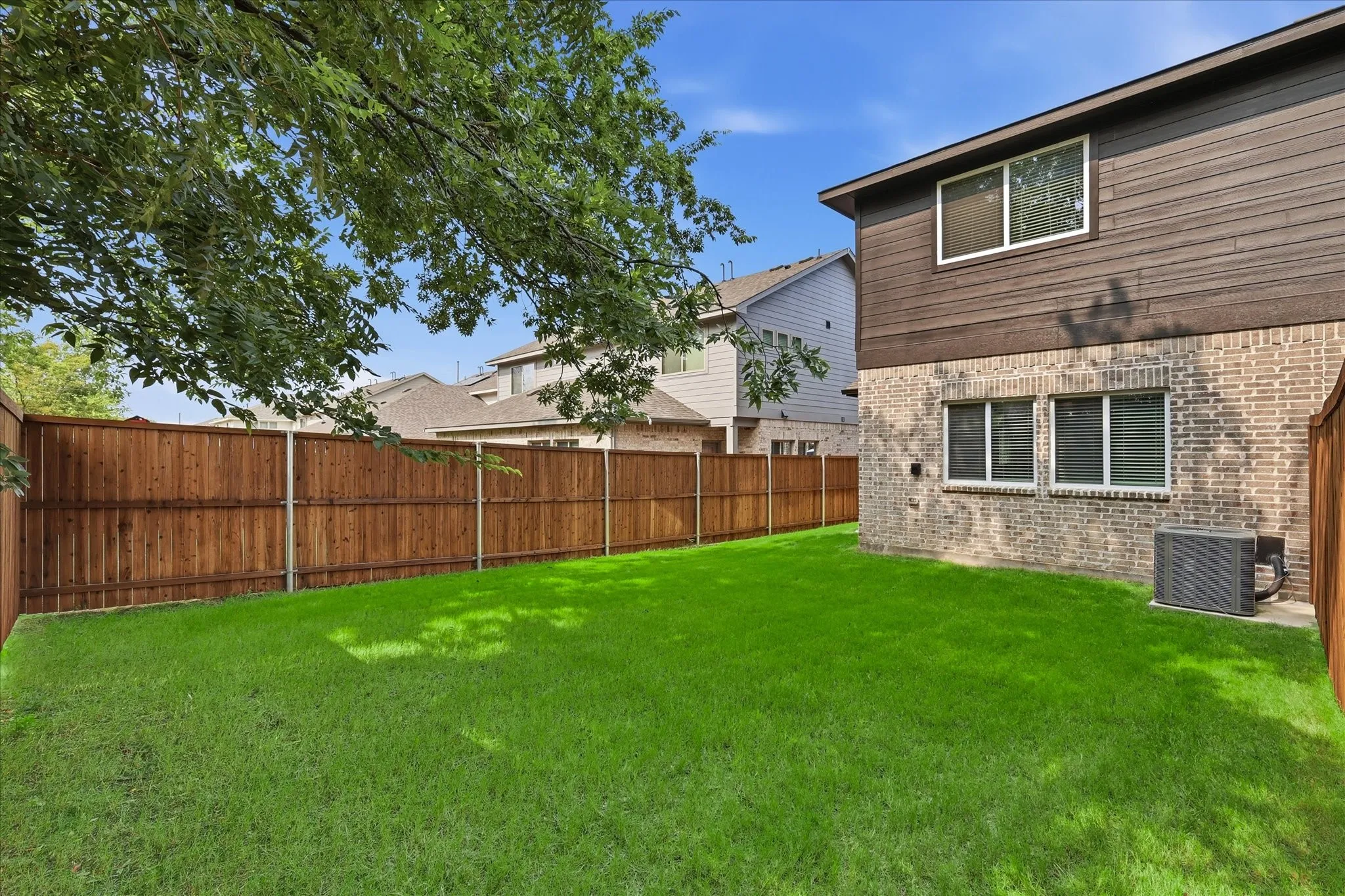 Expansive backyard featuring a lush, manicured lawn bordered by wood-finish privacy fencing